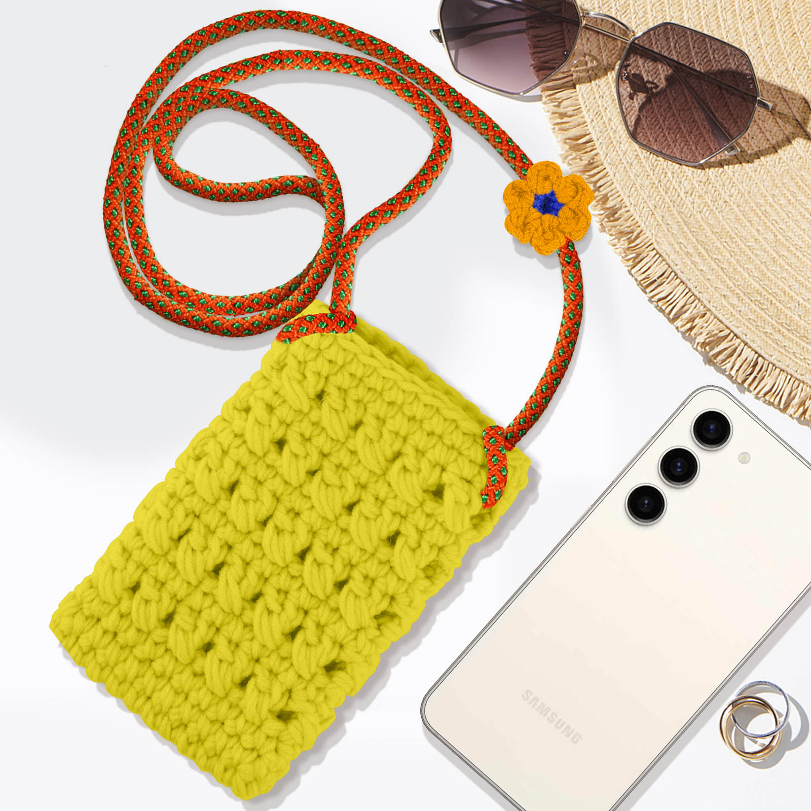 Custodia per telefono all'uncinetto gialla con cinturino rosso e arancione, con occhiali da sole e cappello.