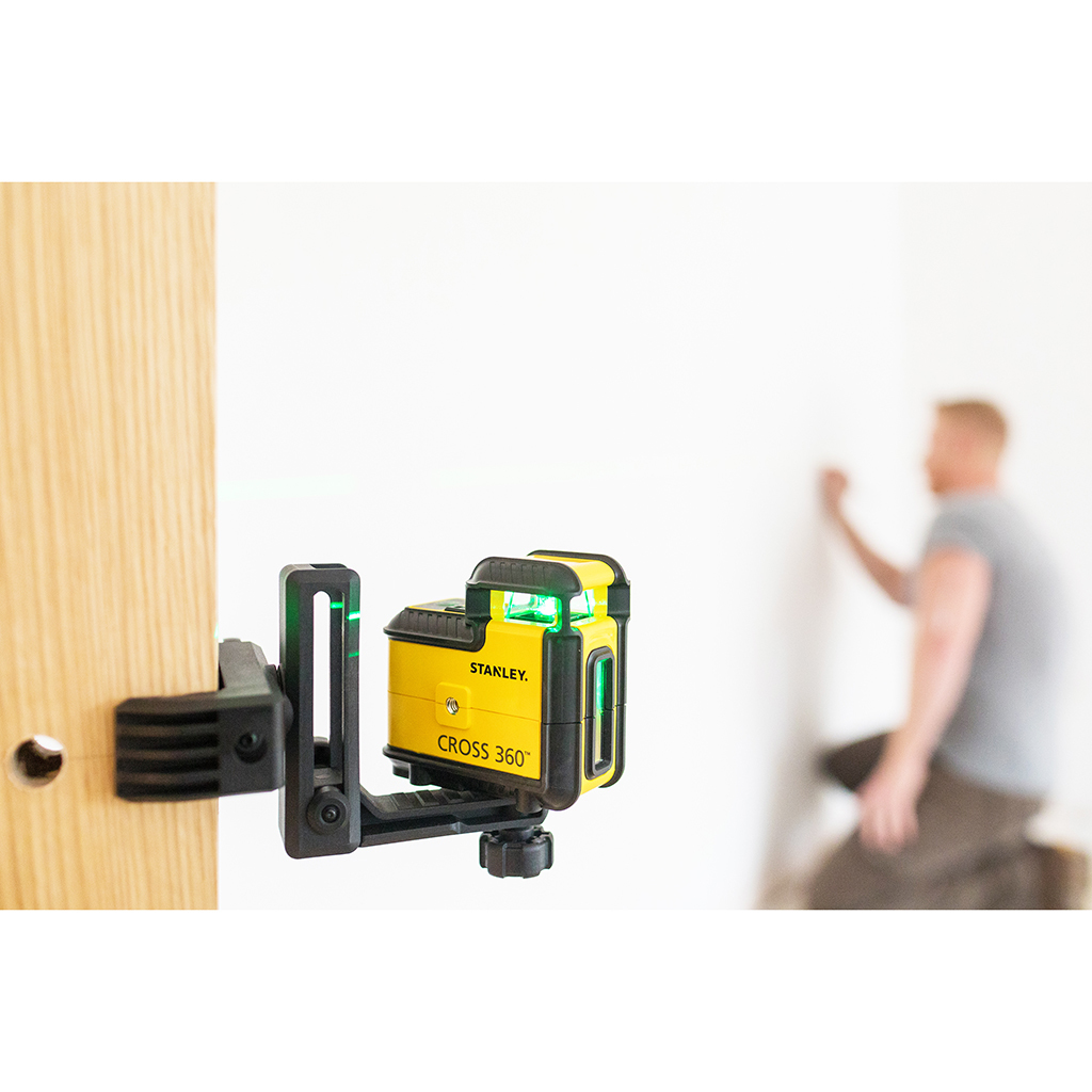 Żółto-czarny poziom laserowy na ścianie. Mężczyzna w tle, w pobliżu białej ściany.