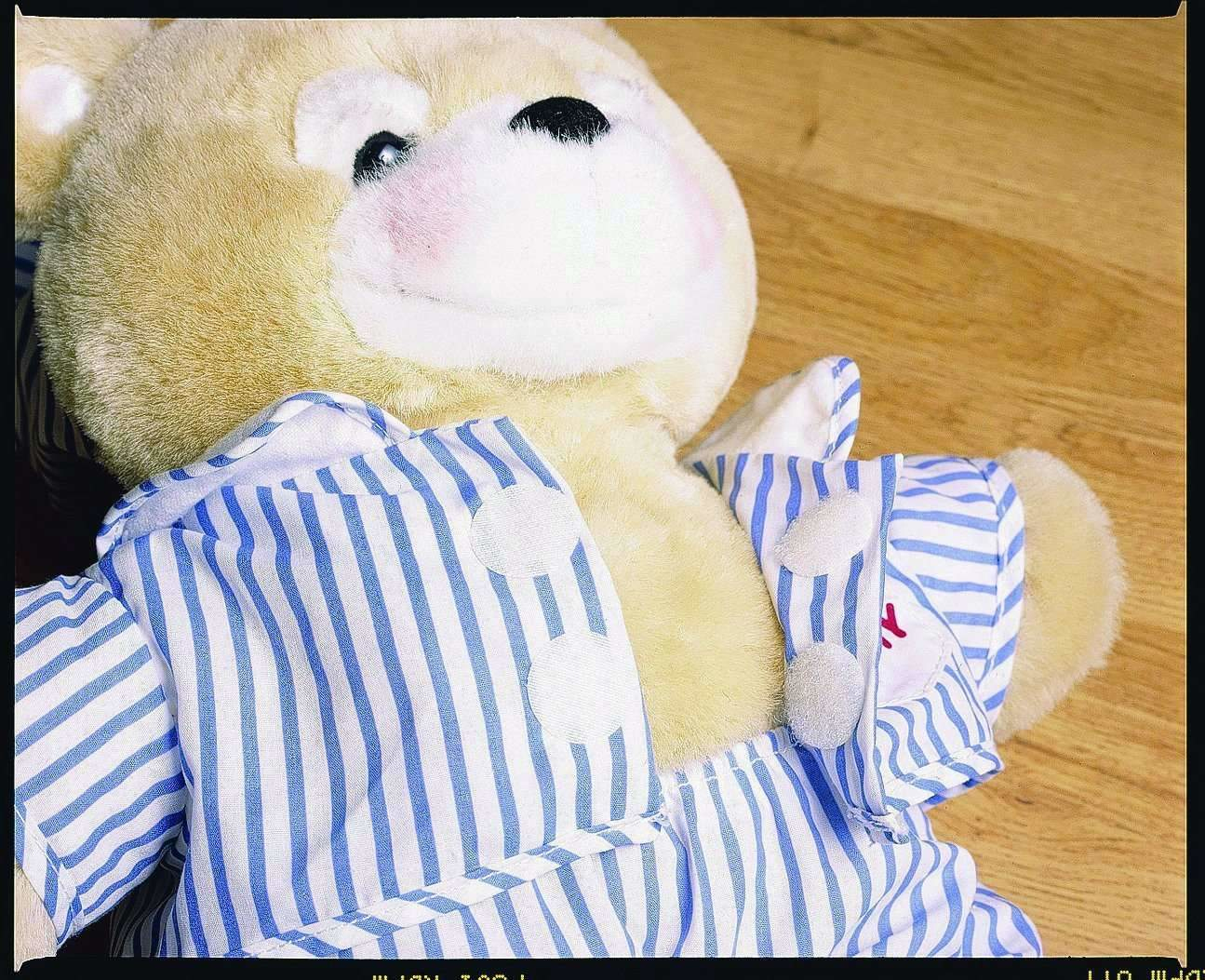 Un orsacchiotto che indossa un pigiama a righe blu e bianche. L'orso è beige.