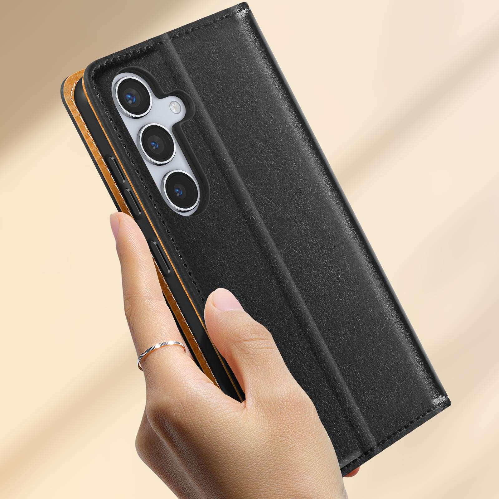 Mano che tiene una custodia nera per telefono con finiture dorate, con un telefono dentro.
