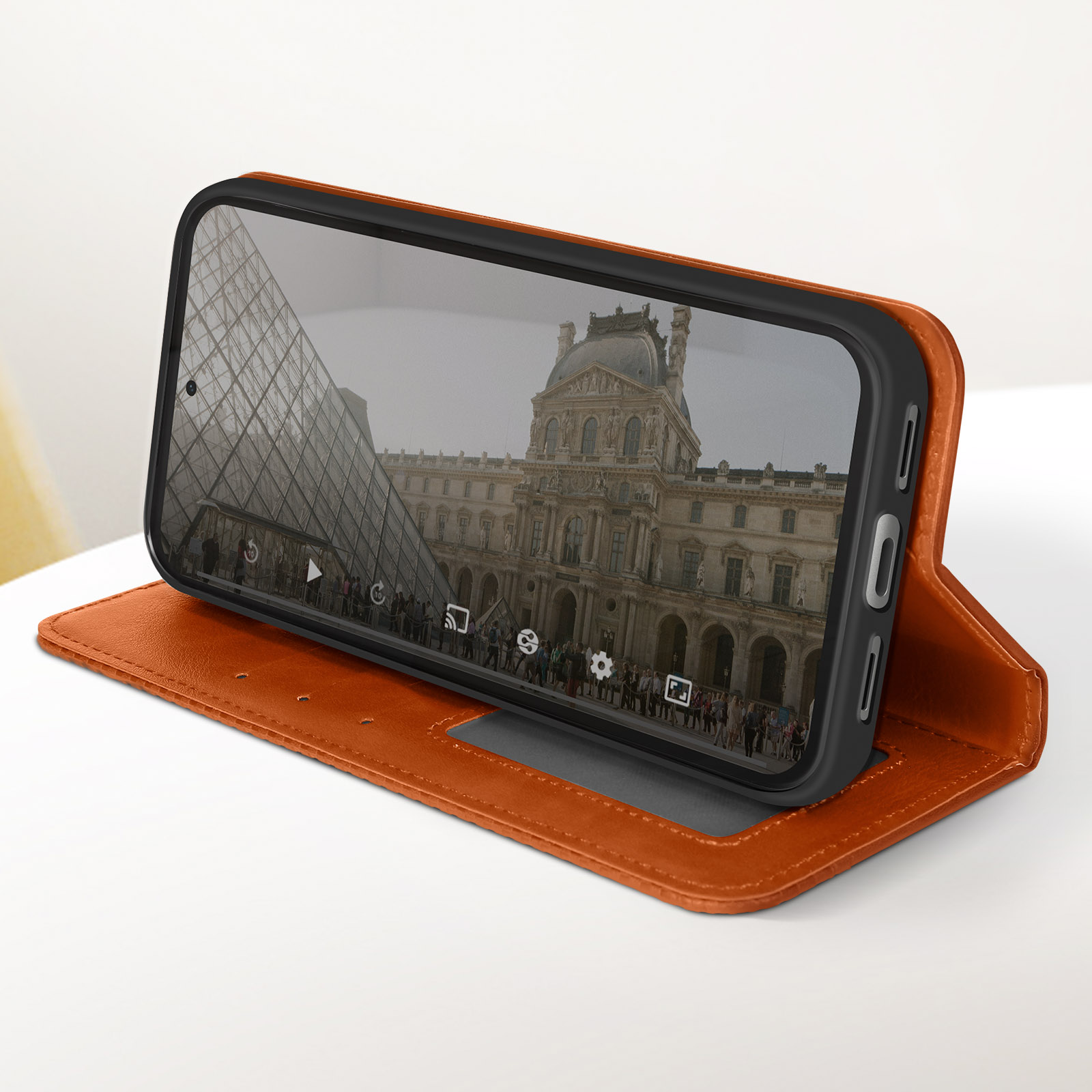 Custodia per telefono aperta con un telefono che mostra il Louvre, Parigi, su una superficie bianca.