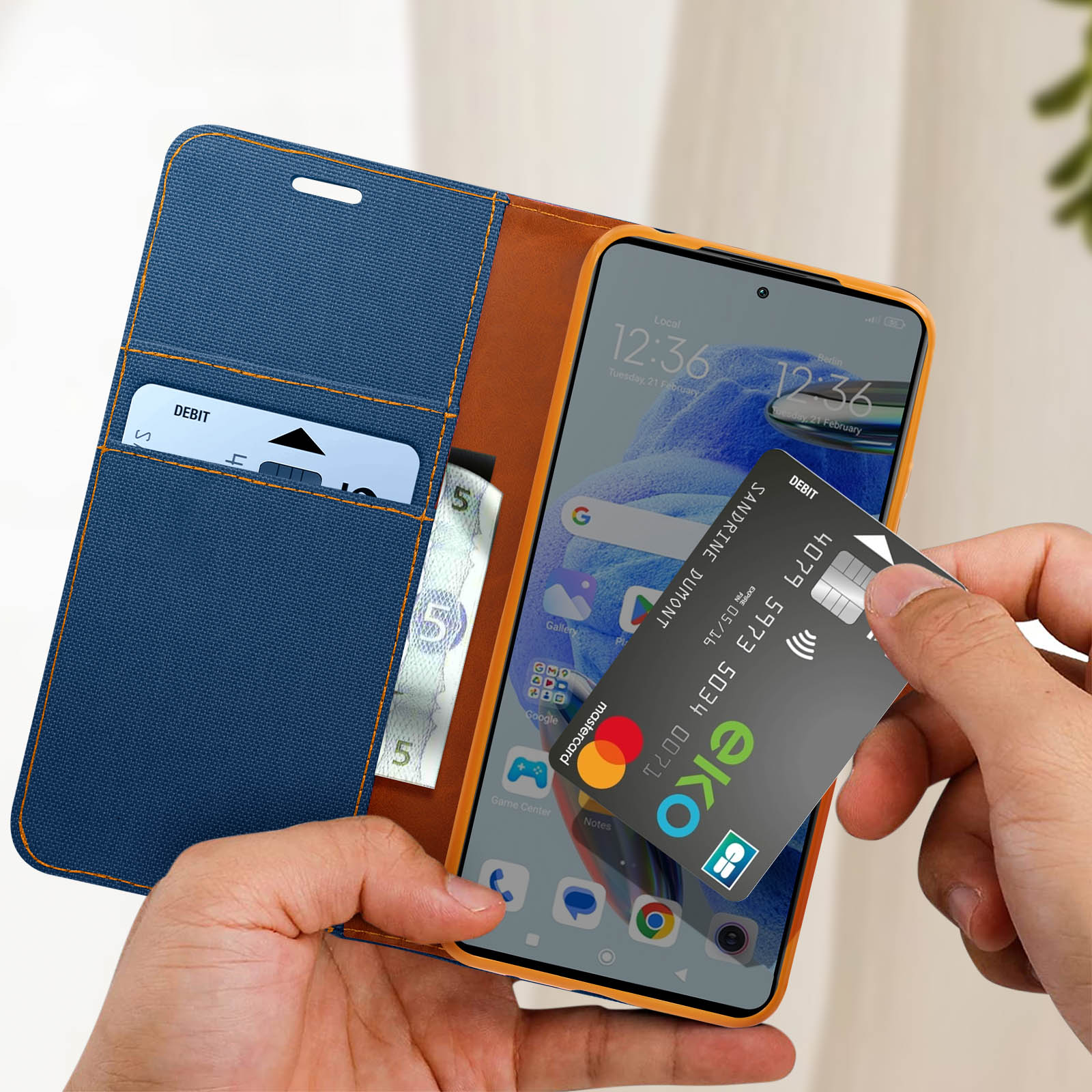 Mani che tengono una custodia per telefono blu e marrone con telefono e carta all'interno.