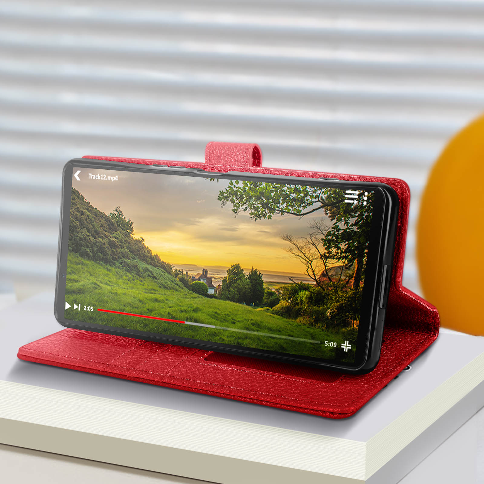 Custodia per telefono rossa, aperta, che mostra un telefono con un video in riproduzione.