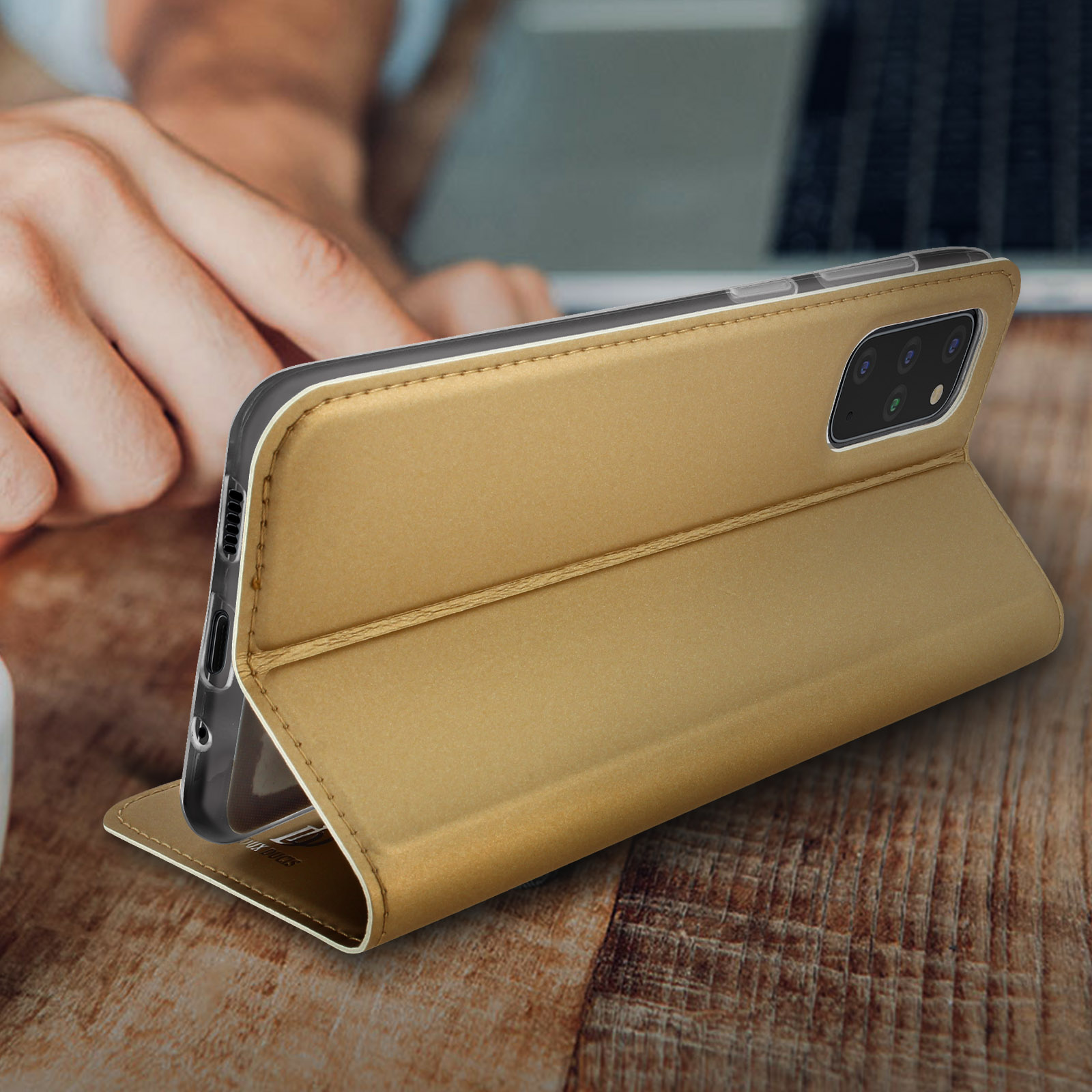 Telefono in una custodia dorata. La custodia è aperta, appoggiata su un tavolo di legno.