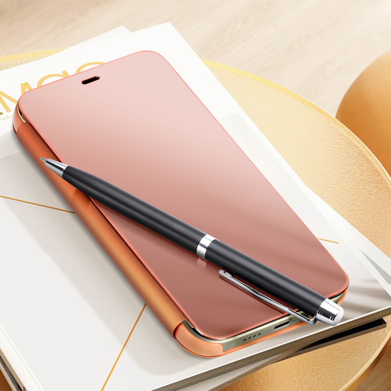 Telefono oro rosa con penna su una superficie bianca e dorata. Una penna è appoggiata sul telefono.
