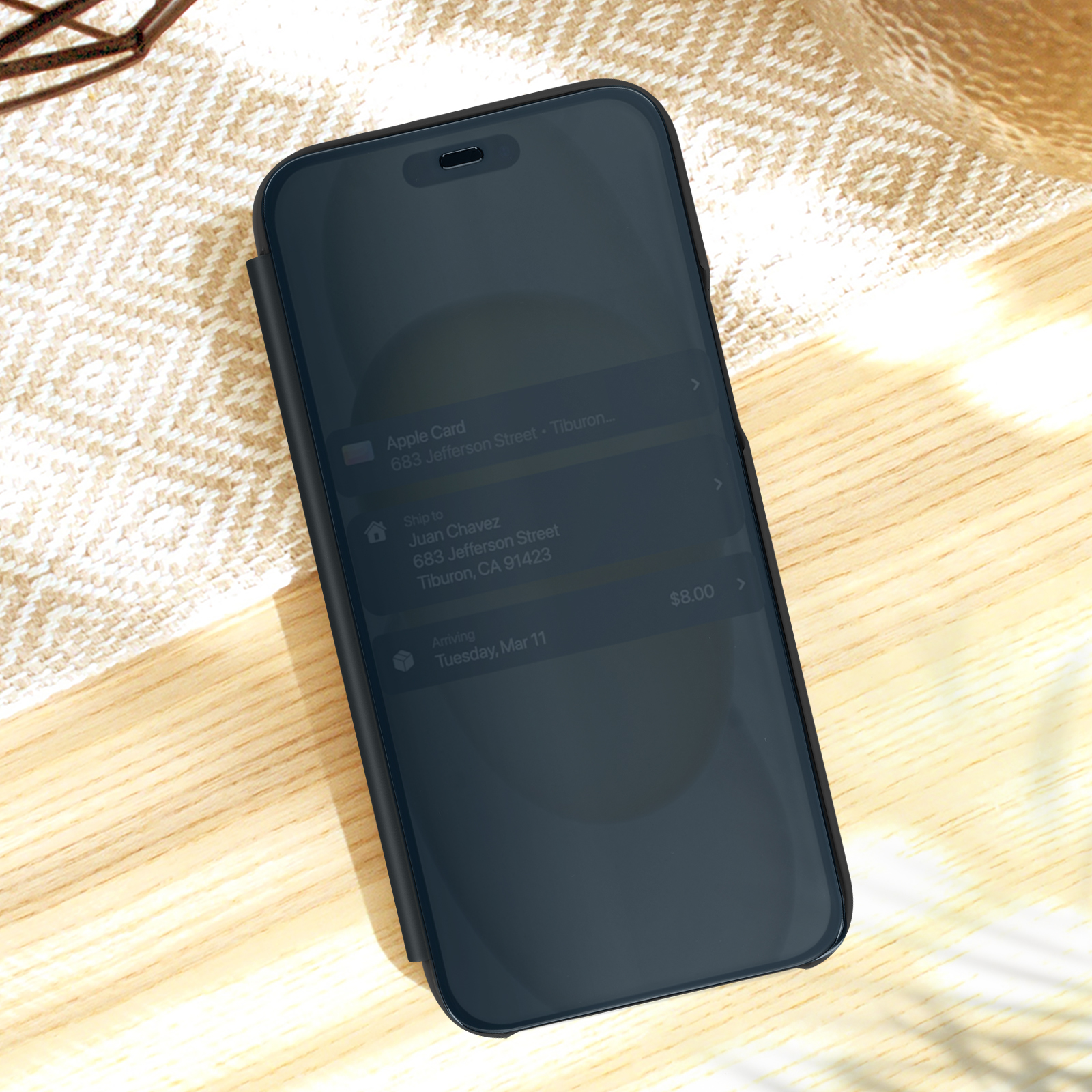 Telefono nero in custodia, mostra uno schermo con mappa. Sfondo tavolo in legno.