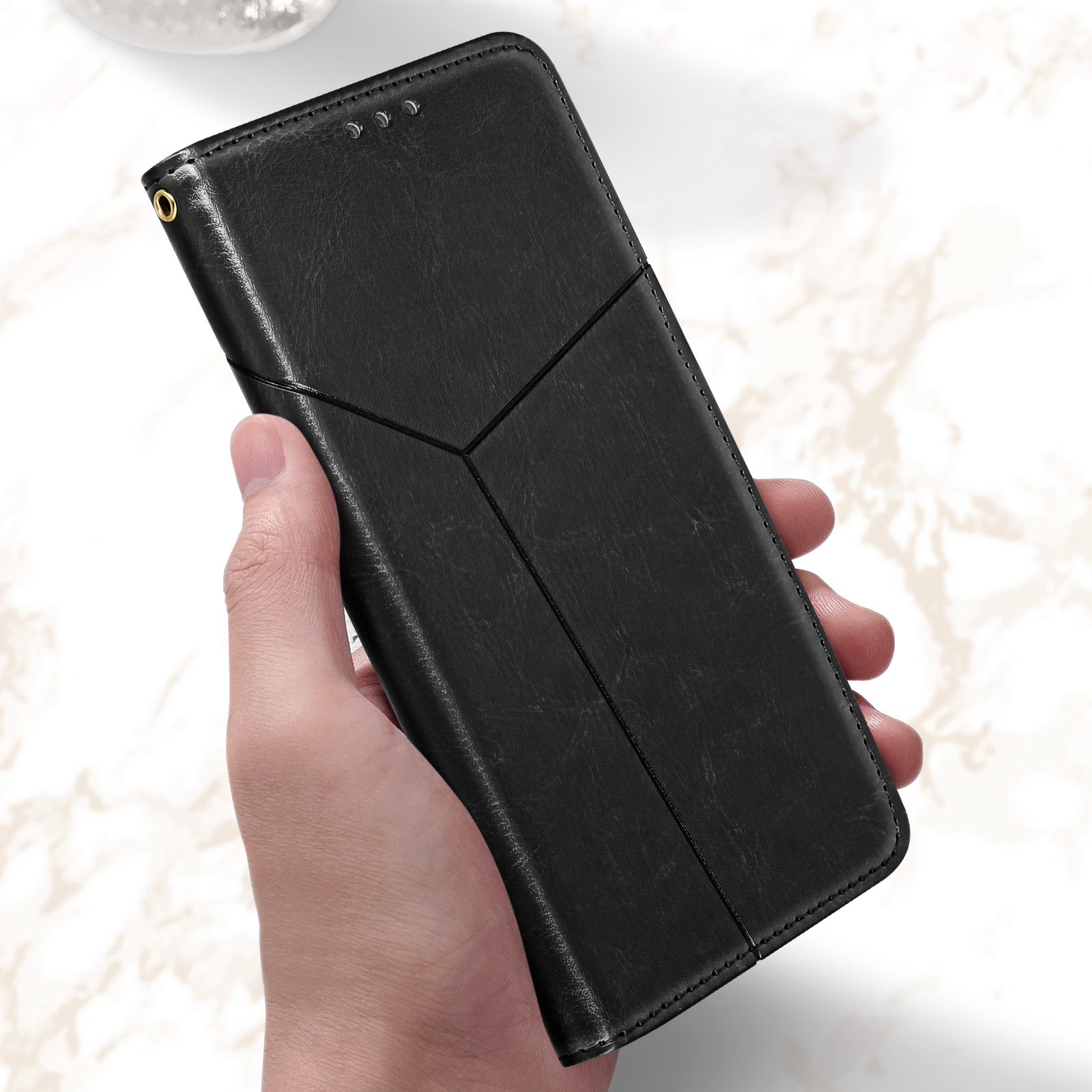 Mano che tiene una custodia per telefono nera con un design geometrico. La custodia è chiusa.