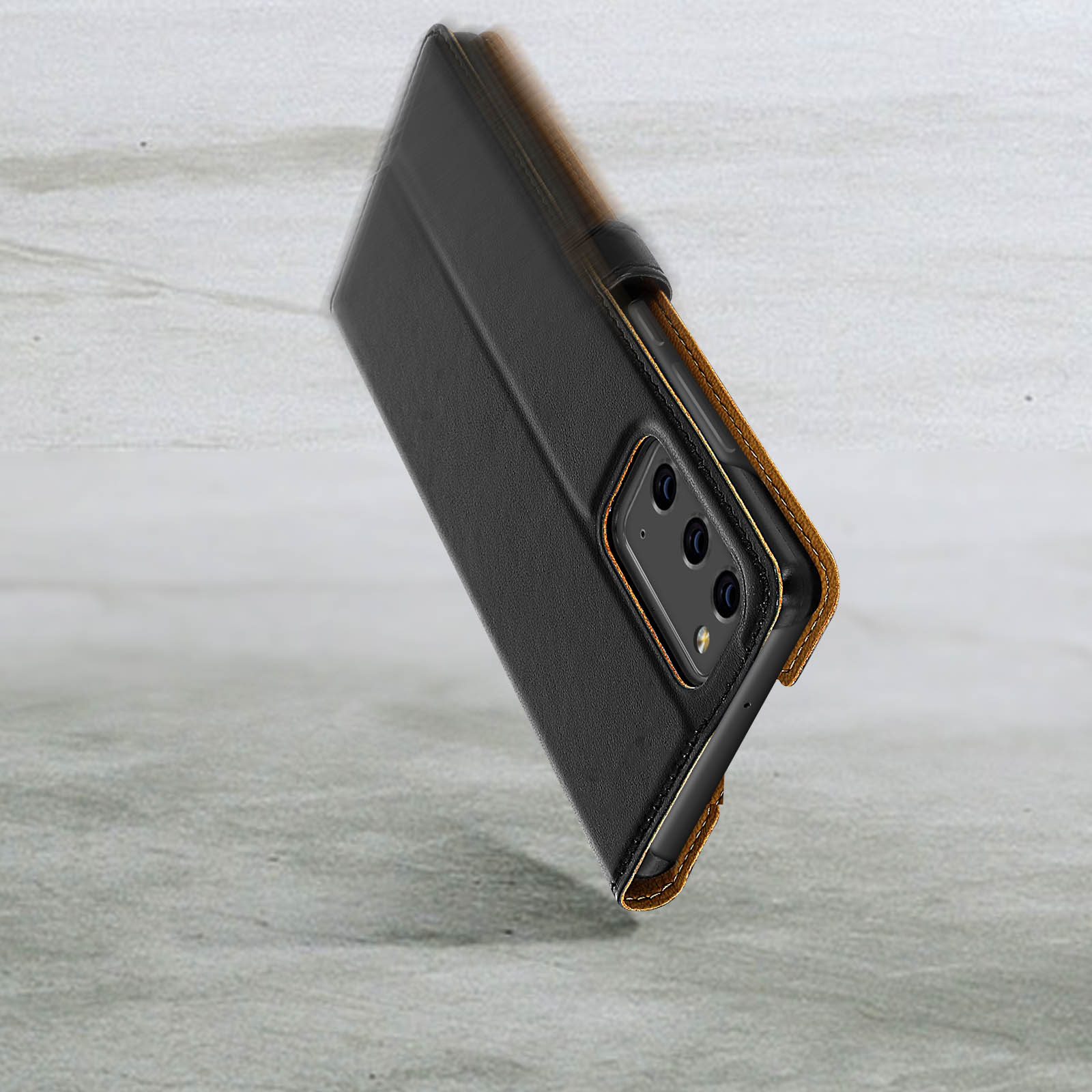 Un telefono in una custodia nera sta cadendo, con uno sfondo chiaro.