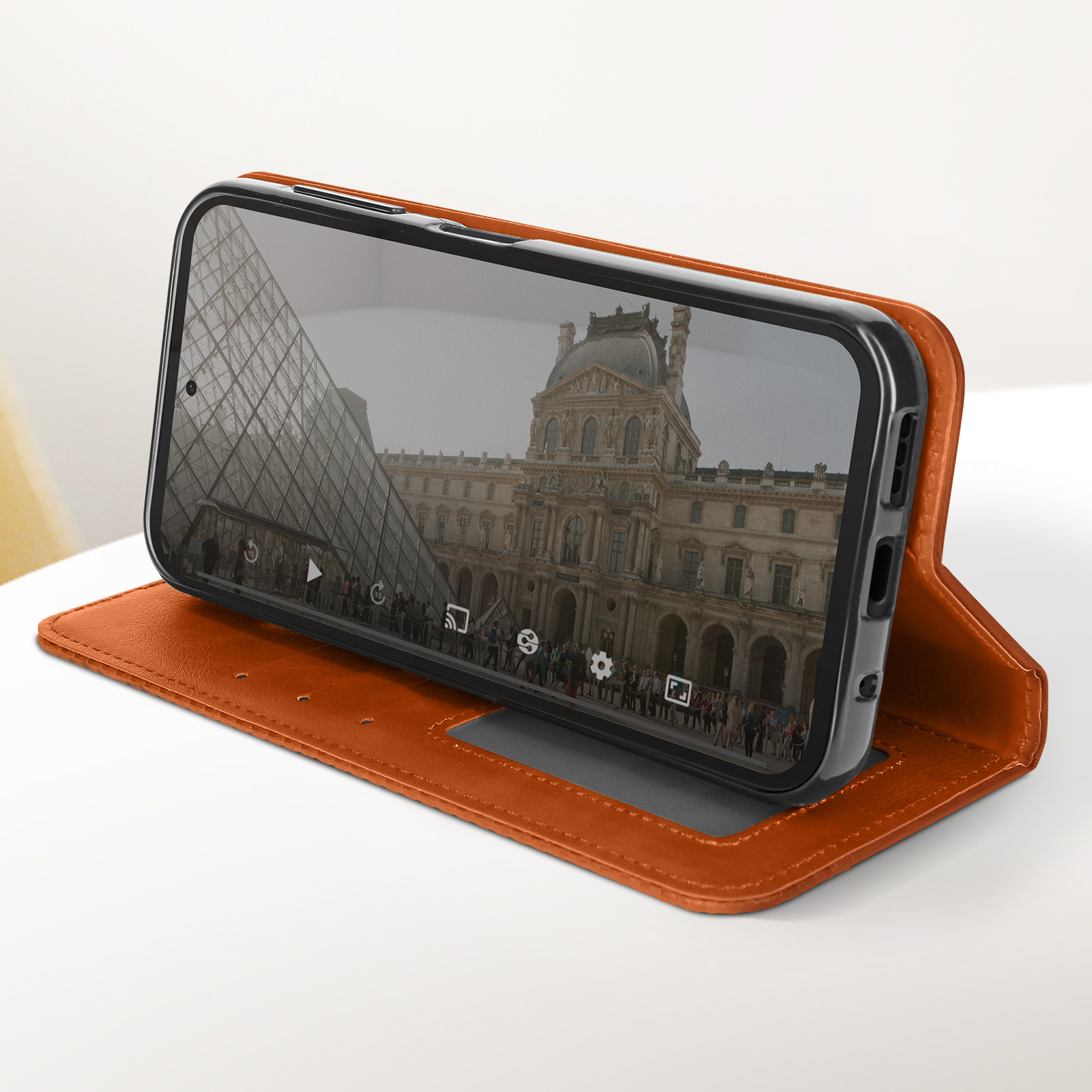 Ein Telefon in einer offenen braunen Hülle, das ein Bild eines Gebäudes mit einer gläsernen Pyramide zeigt.