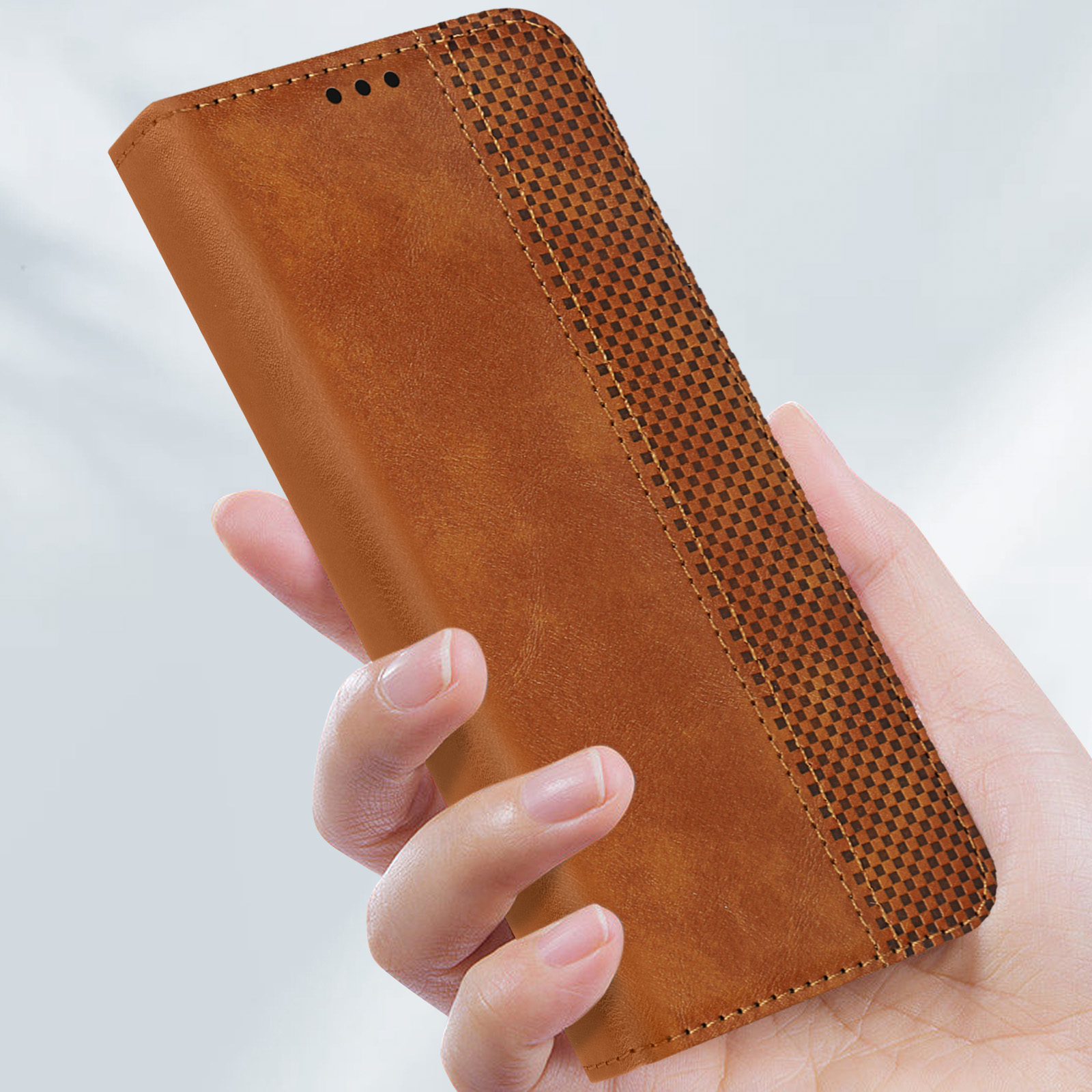 Hand hält eine braune Handyhülle mit kariertem Muster und Steppnähten.