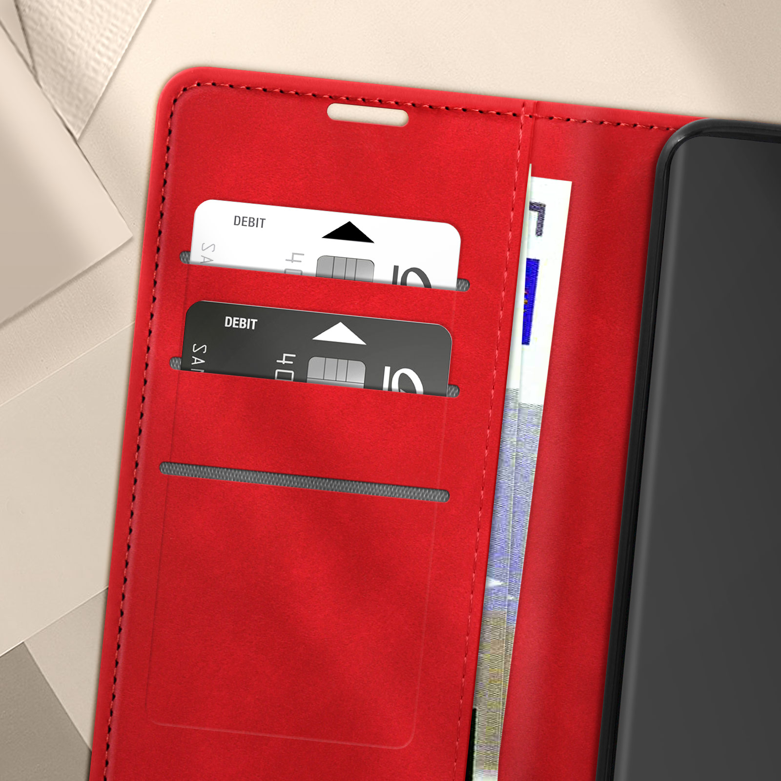 Custodia rossa per telefono aperta, mostra due carte di debito e un po' di denaro cartaceo.
