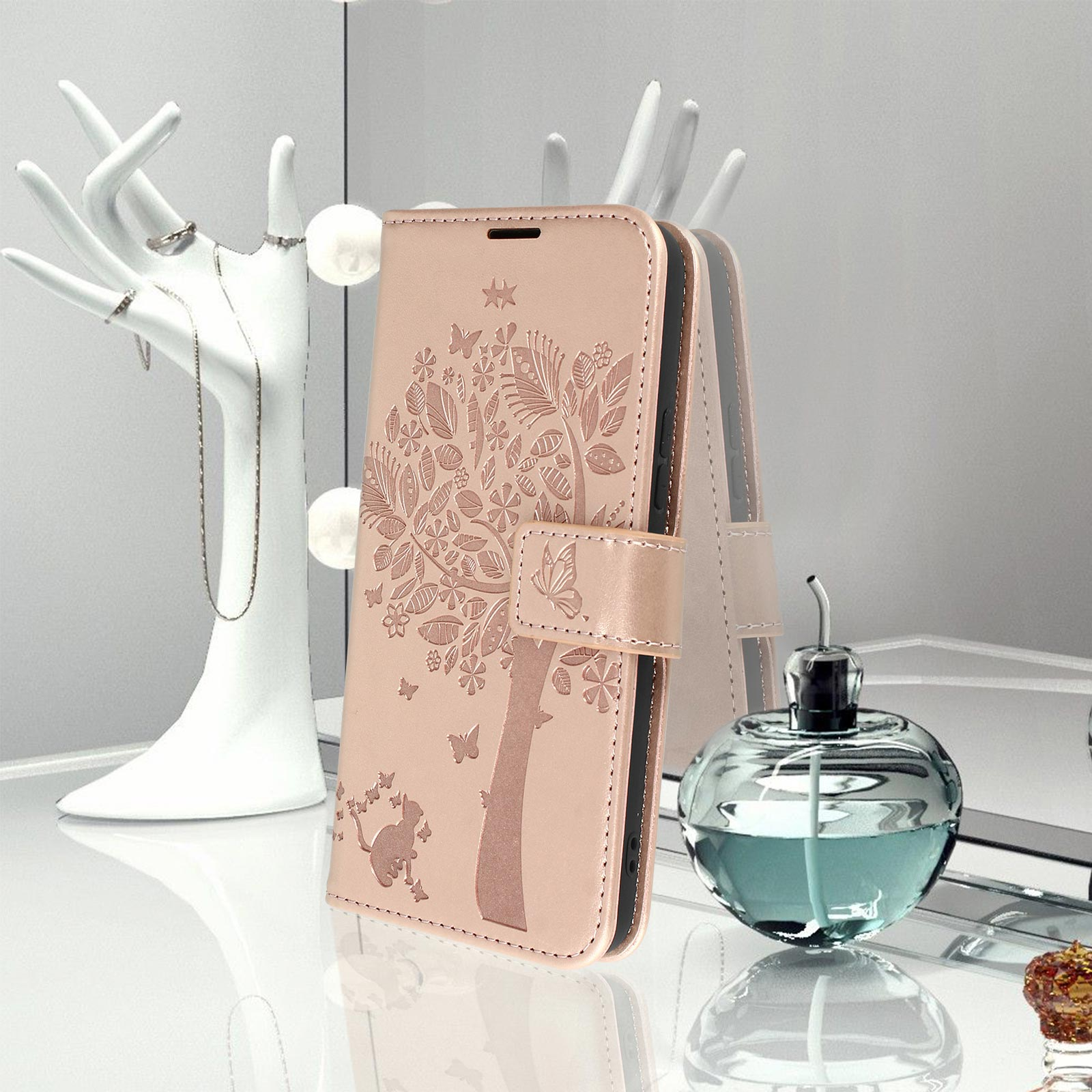 Custodia rosa per telefono con un disegno ad albero. Bottiglia di profumo e portagioie sullo sfondo.