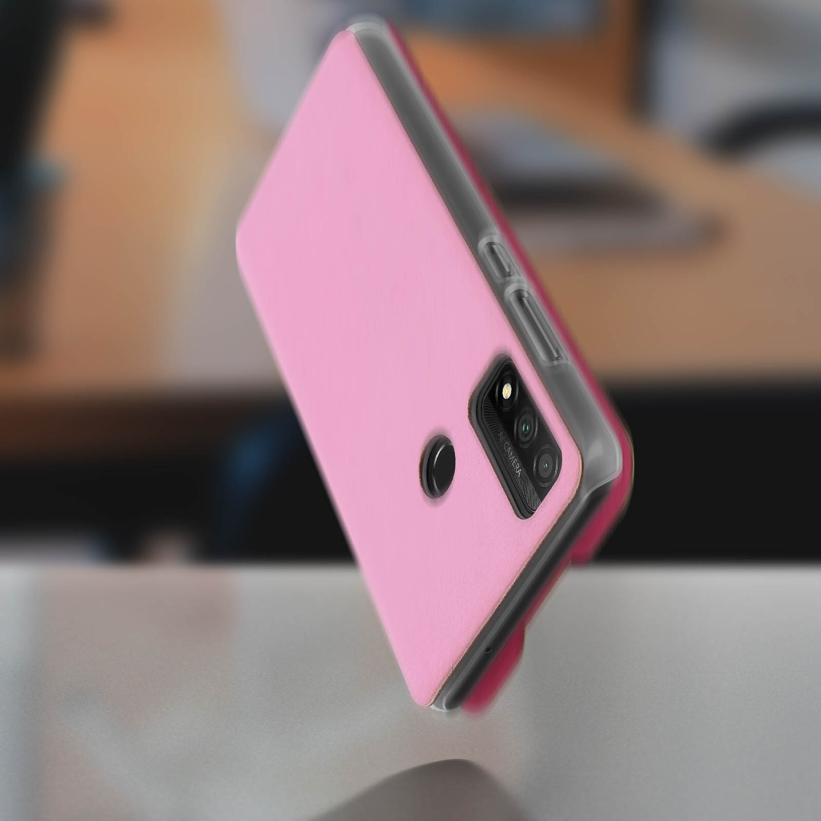 Custodia rosa per telefono sul tavolo. Fotocamera e flash visibili sul retro.