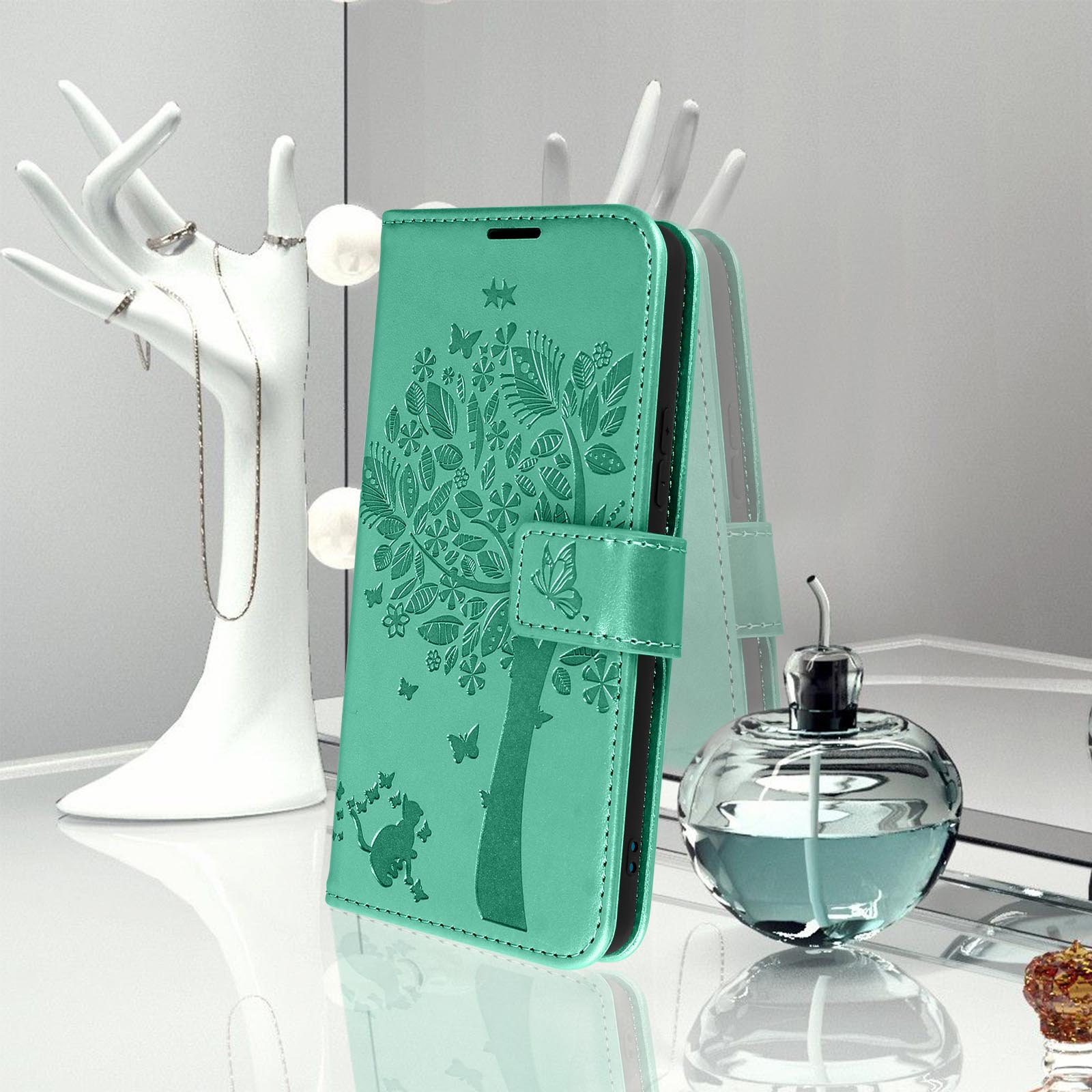 Custodia teal per telefono con design ad albero. Fiori e farfalle. Specchio e profumo sullo sfondo.