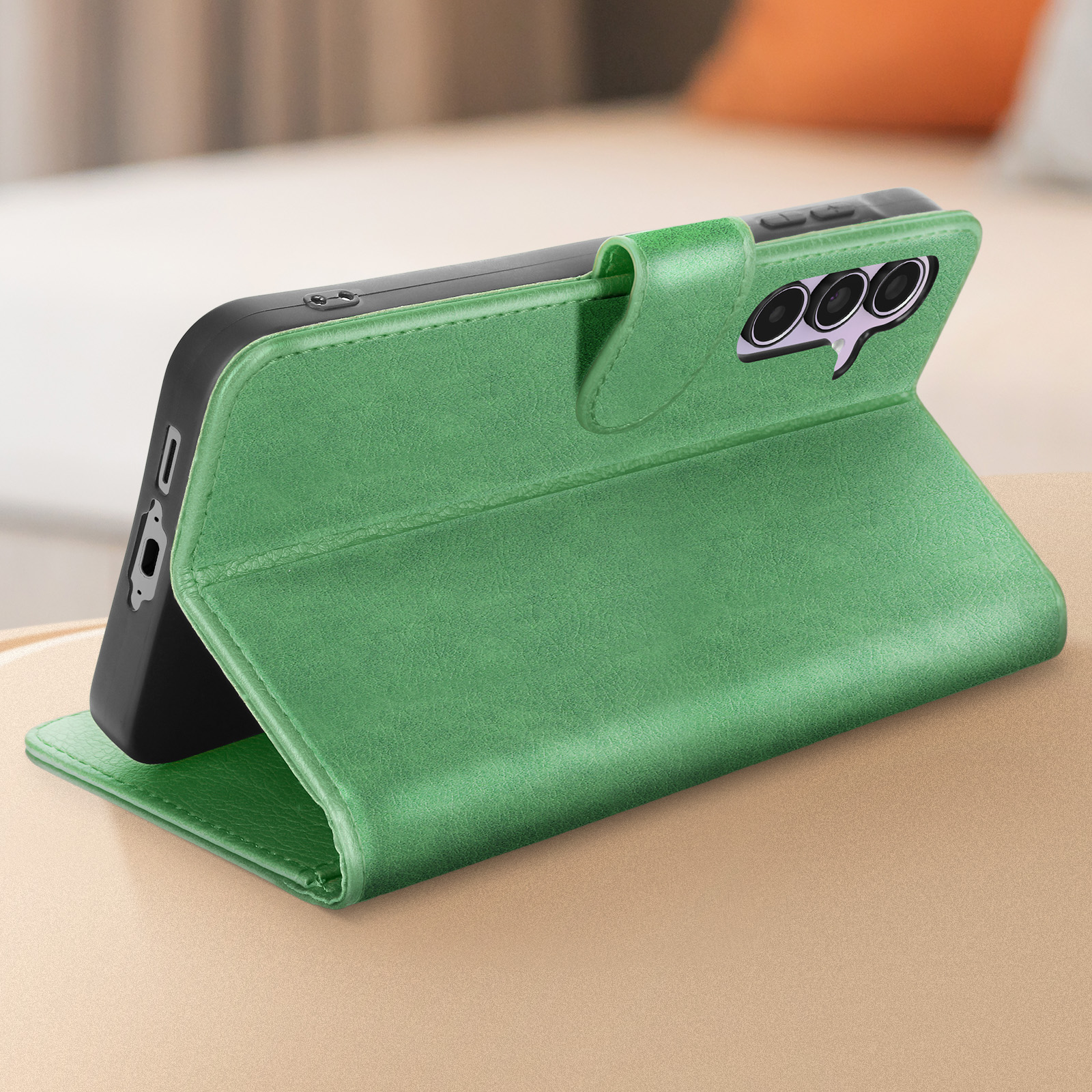 Custodia per telefono in pelle verde, aperta e in piedi. C'è un telefono dentro. La custodia è su un tavolo.