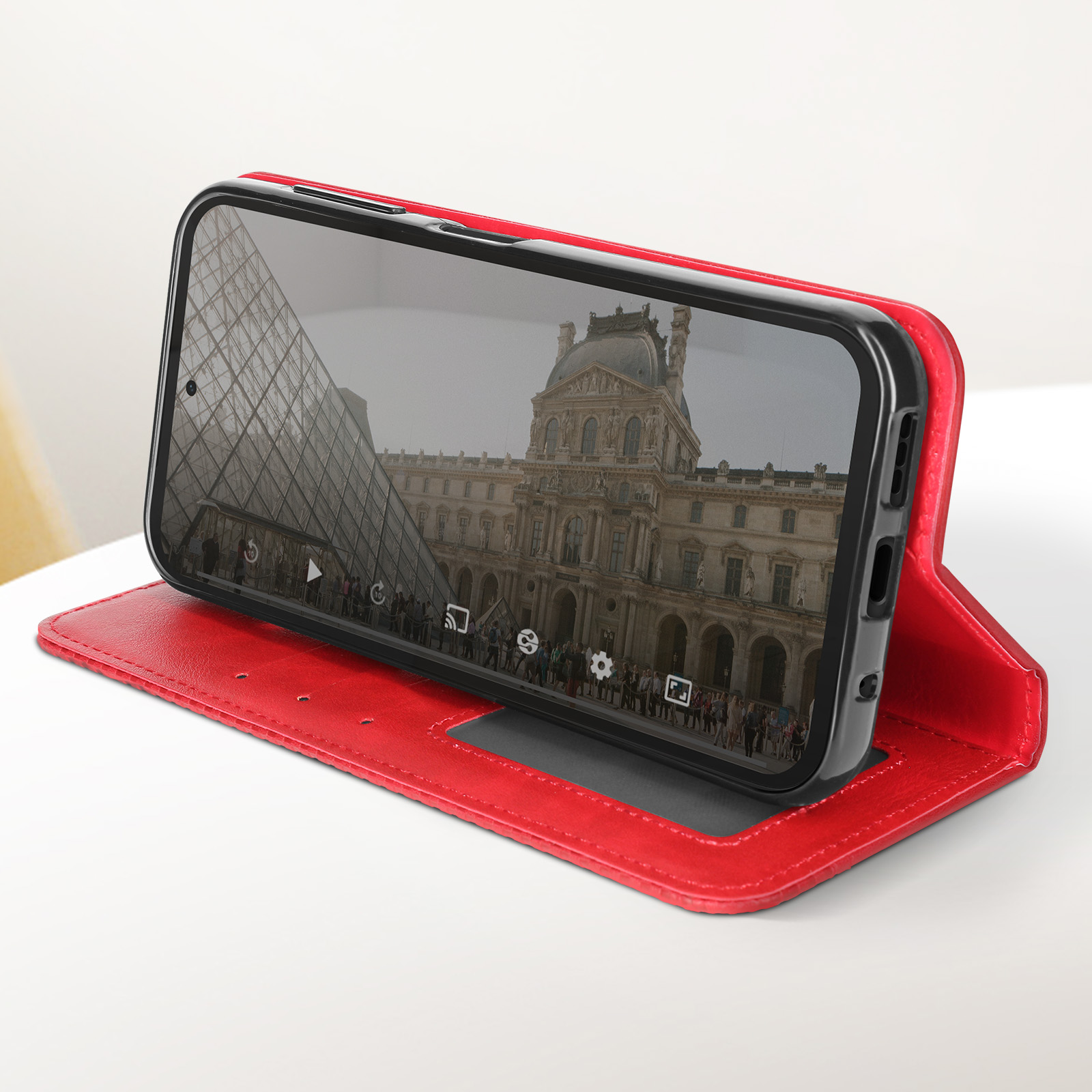 Un telefono mostra una scena del Louvre. Il telefono è in una custodia rossa.