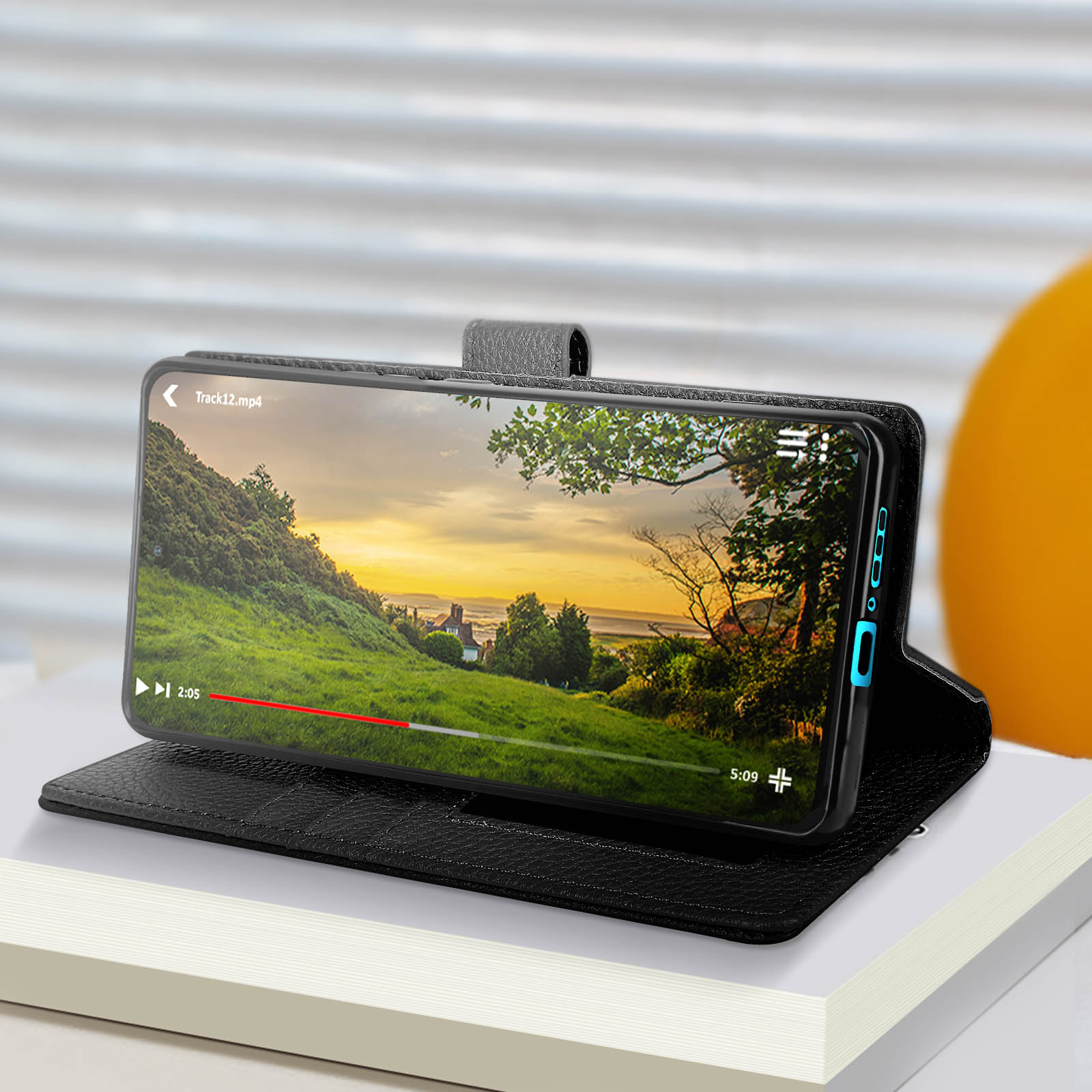 Telefono in una custodia mostra un video. La custodia è su un libro. Sfondo sfocato.