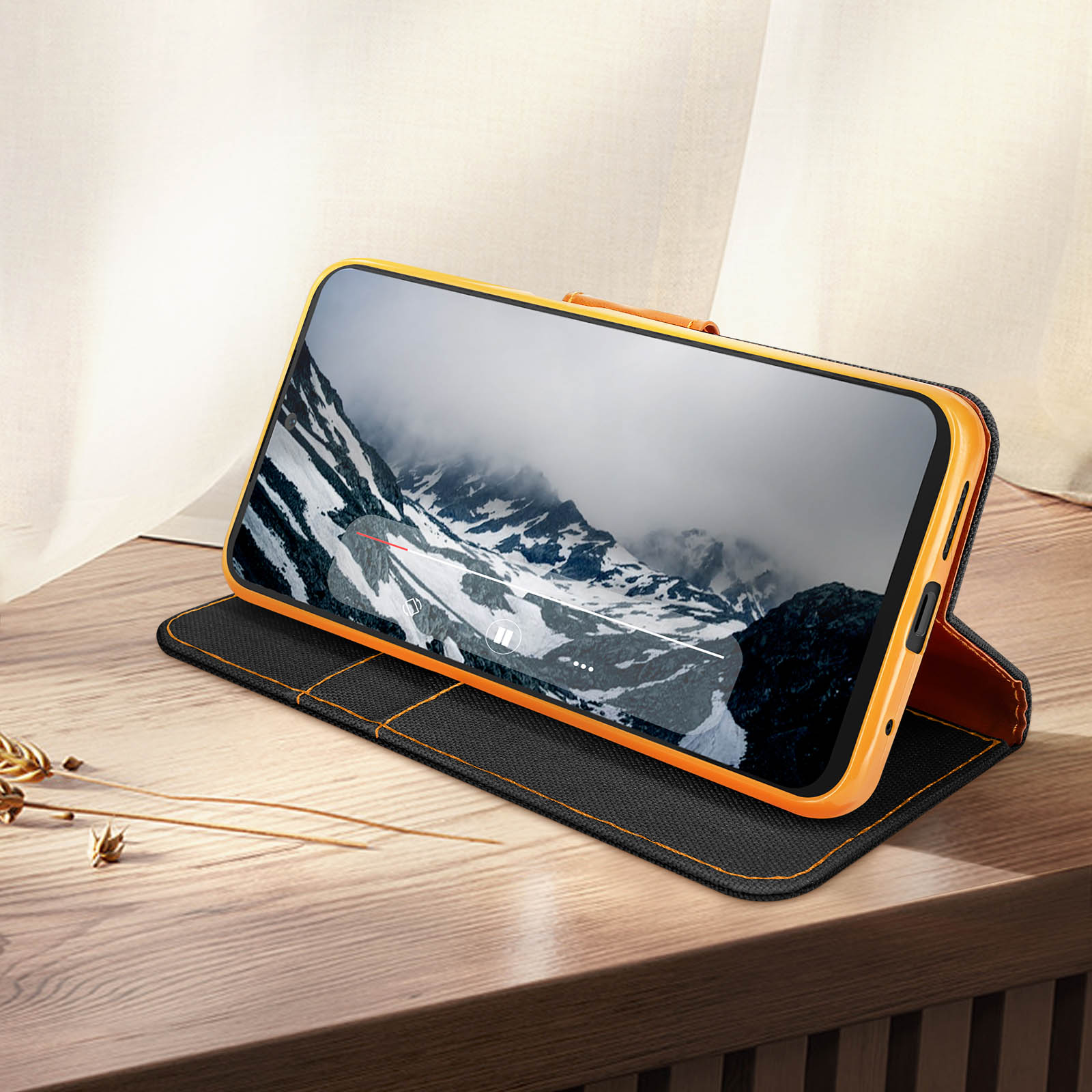 Telefono in custodia con supporto, mostra video di montagna. Superficie in legno.