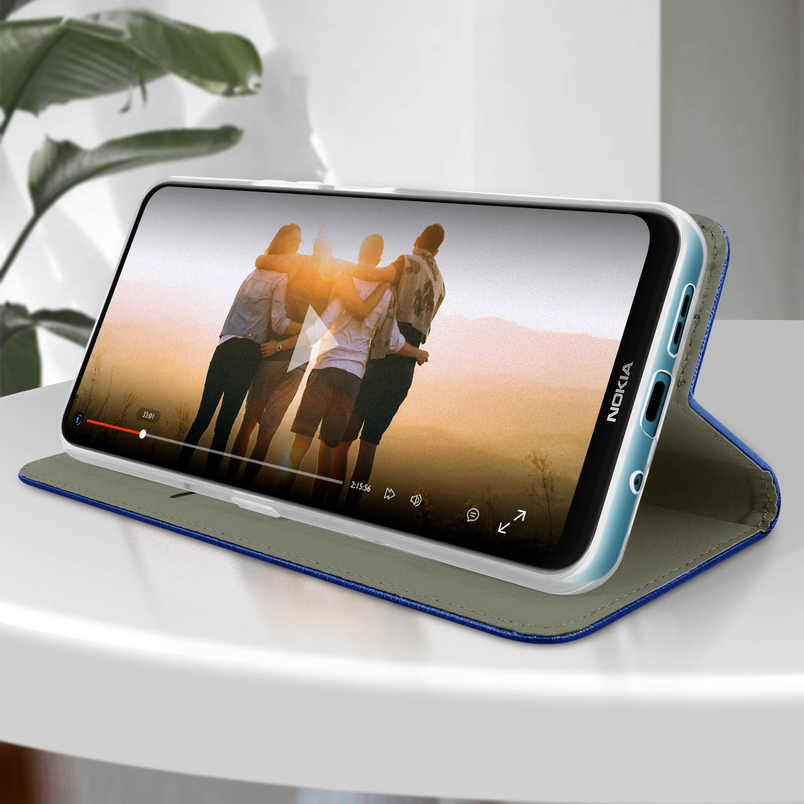 Telefono aperto che mostra un video, su un tavolo. Una donna lo tiene.