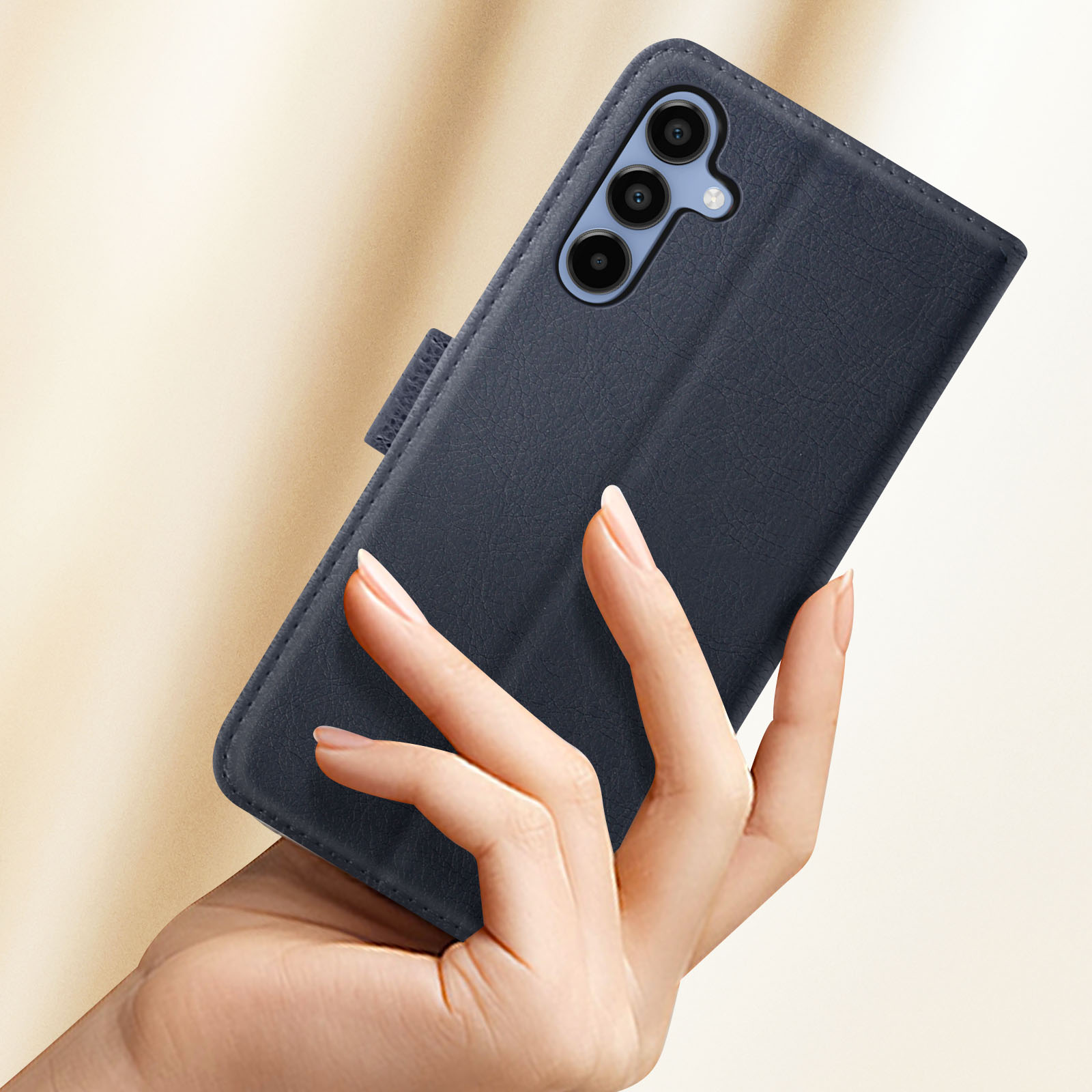 Una mano di donna che tiene un telefono blu navy in una custodia abbinata. Il telefono ha tre fotocamere.
