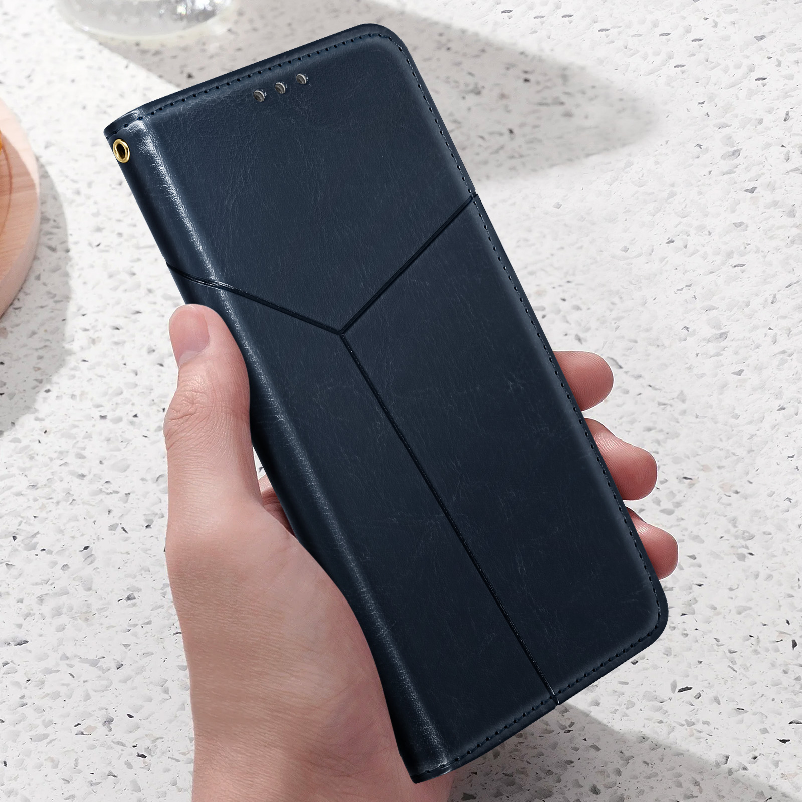 Mano che tiene una custodia blu scuro. La custodia ha un design geometrico.