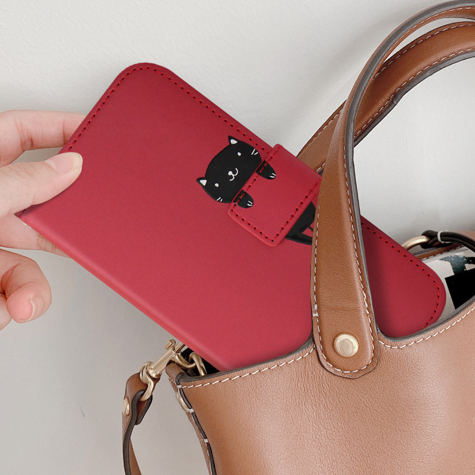 Custodia rossa per telefono con un gatto dei cartoni animati. La custodia è in una borsa marrone.