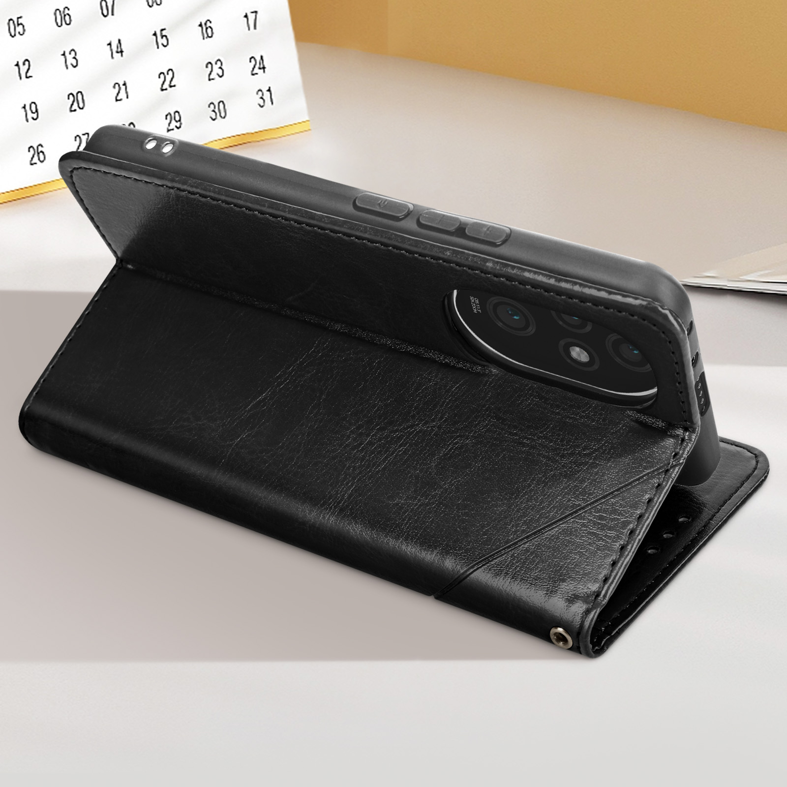 Telefon in schwarzer Lederhülle, offen, aufgestellt. Ein Kalender im Hintergrund.