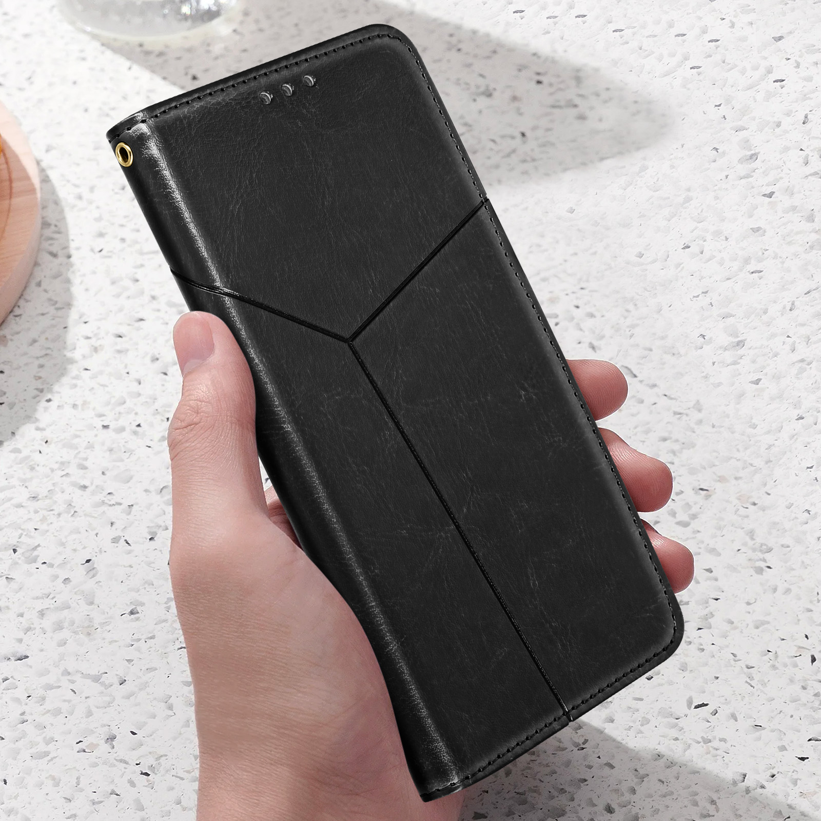 Hand hält schwarze Handyhülle mit dekorativem Design.