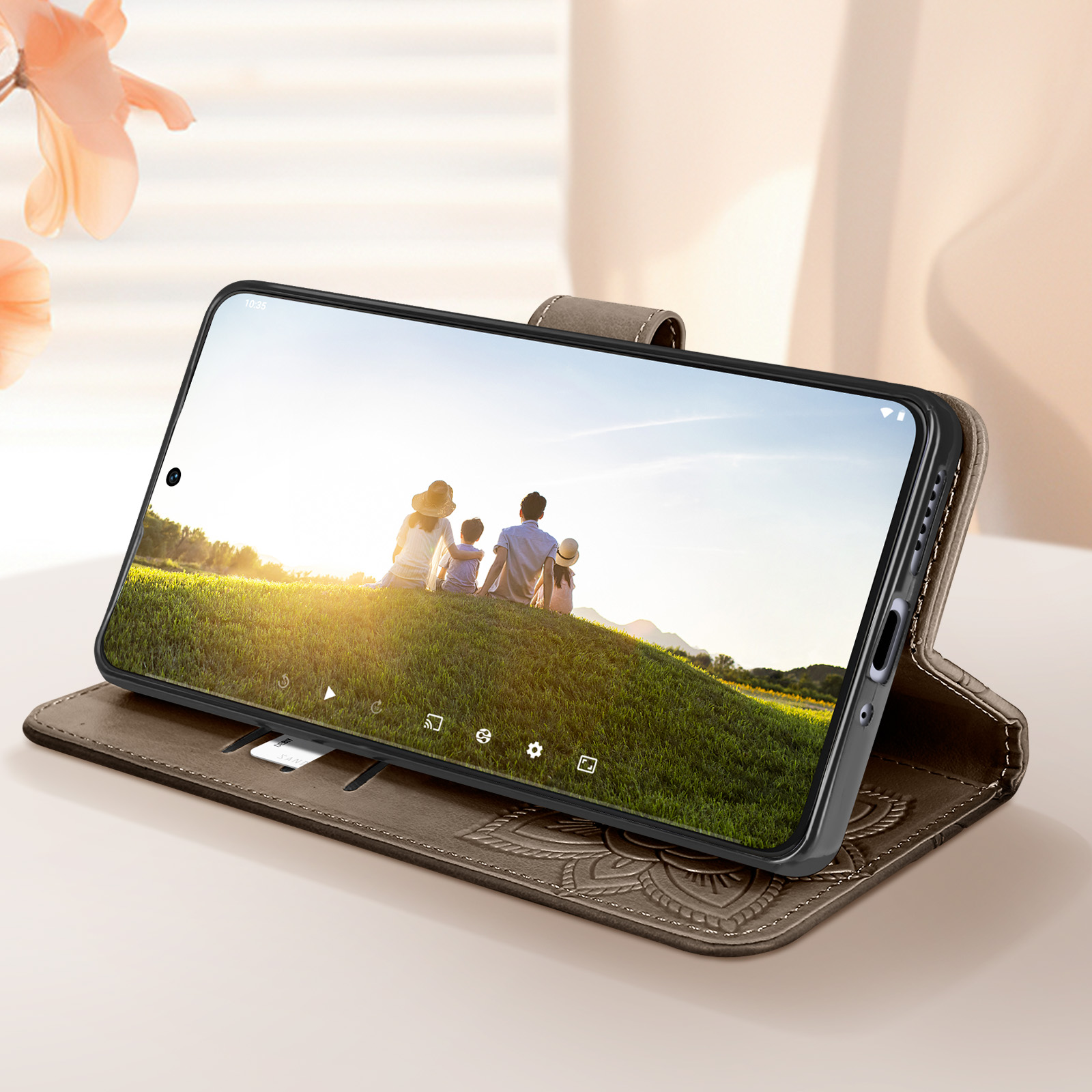 Un telefono in una custodia marrone, che mostra una famiglia in un campo al tramonto. La custodia è aperta.