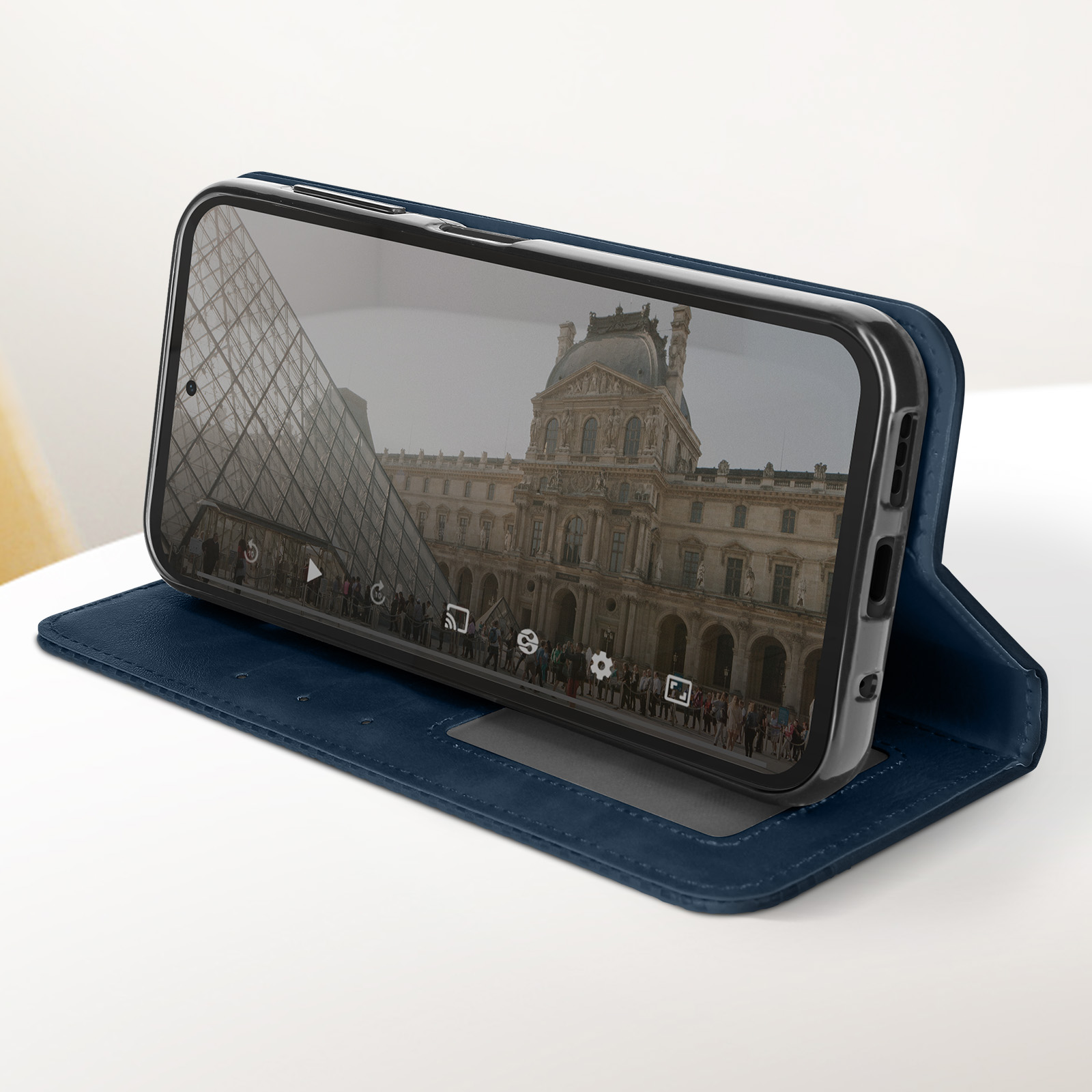 Custodia blu aperta, che mostra un telefono che mostra un'immagine del Louvre. È su un tavolo di marmo.