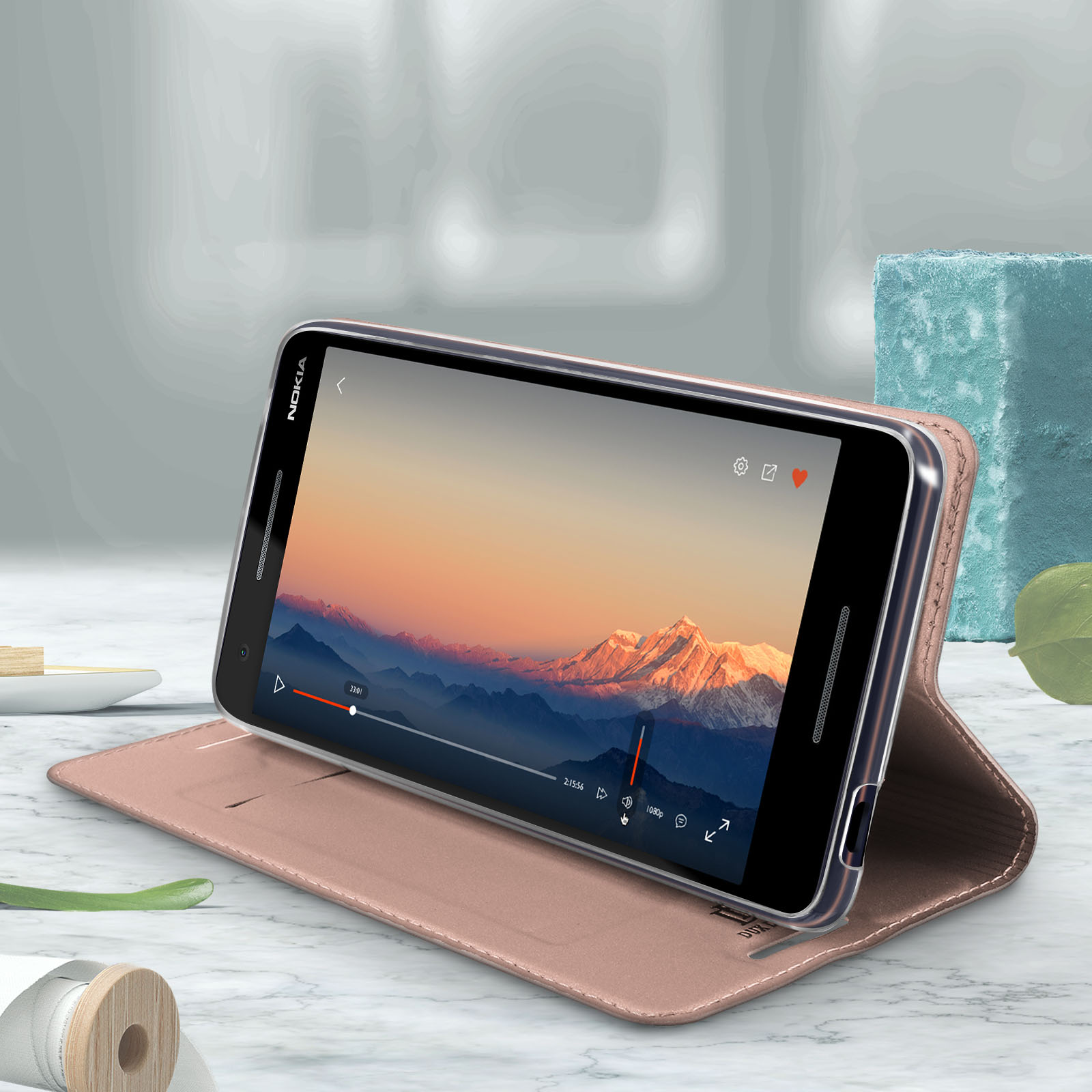 Telefono in una custodia rosa, aperto. Lo schermo mostra un video con vista sulle montagne.