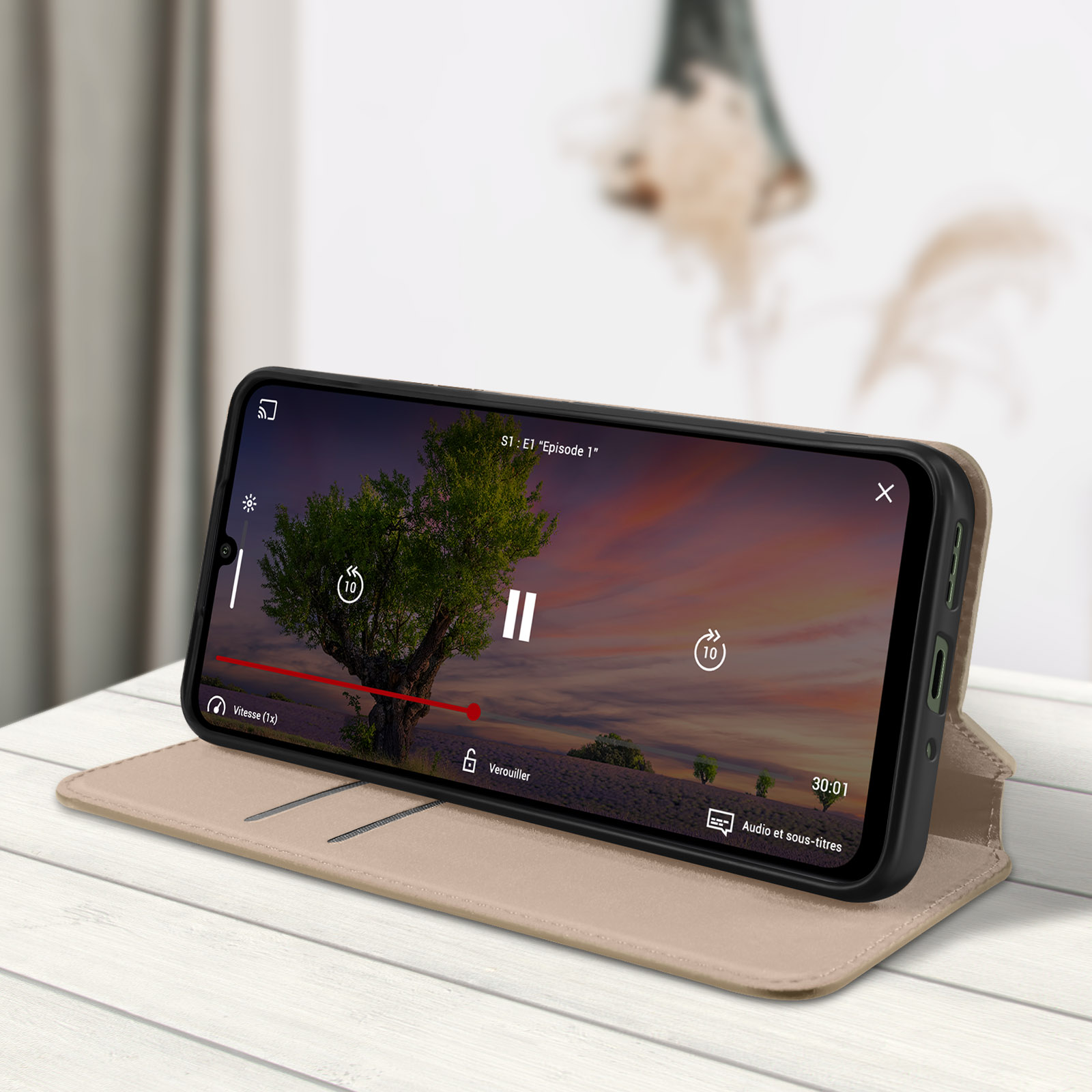 Custodia per telefono che mostra un video di un albero al tramonto. Il telefono è su un tavolo di legno.