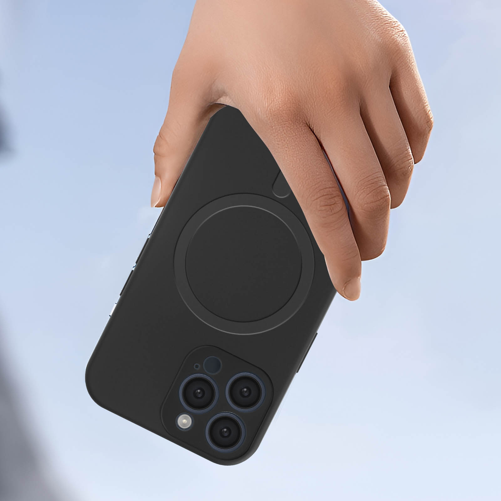 Mano che tiene un telefono nero con custodia. La fotocamera del telefono è visibile. Sfondo cielo blu.