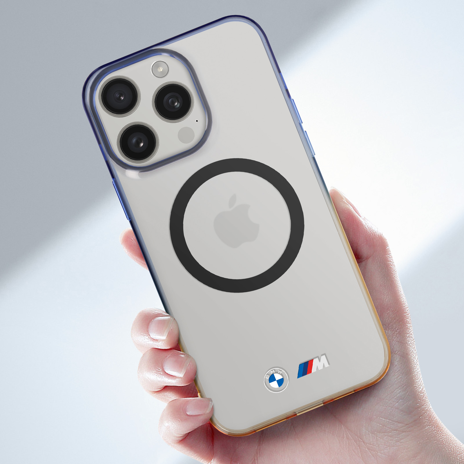 Mano che tiene una custodia trasparente per telefono con logo BMW. Bordo blu e giallo, sfondo bianco.