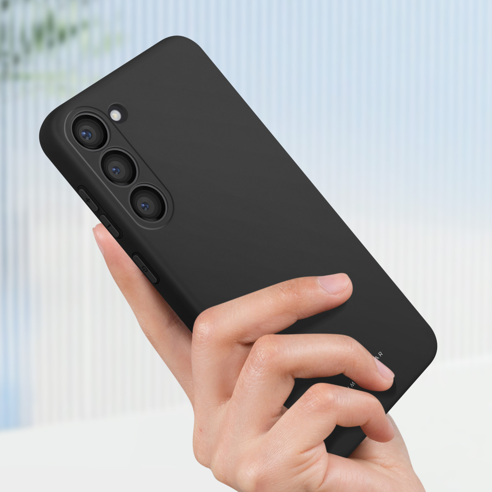 Una mano che tiene una custodia nera per telefono con un design elegante e tre obiettivi della fotocamera.