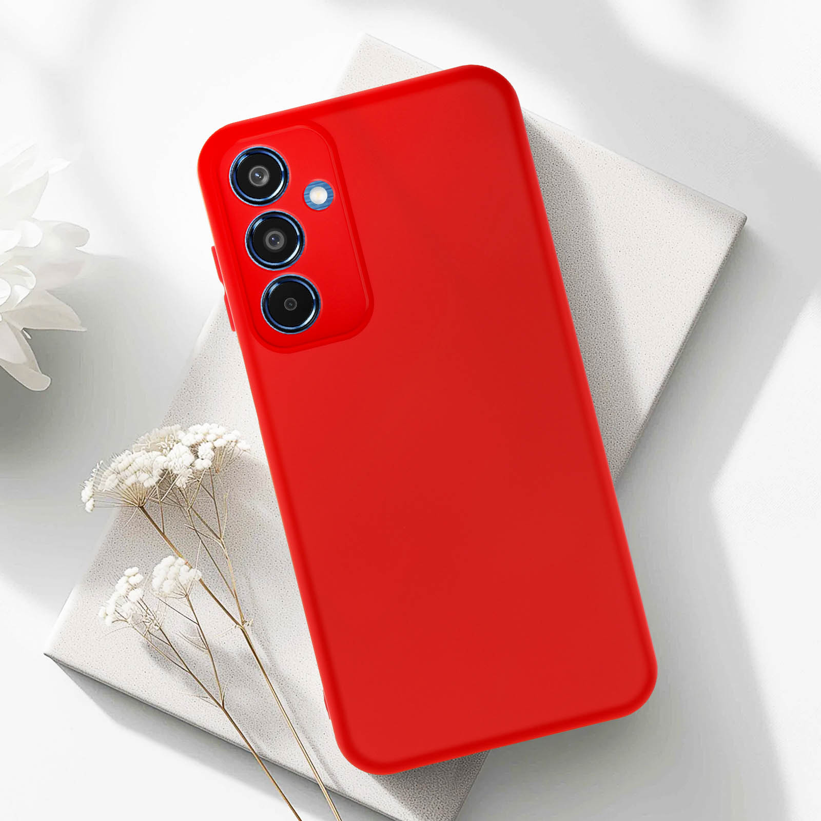 Custodia rossa con tre fotocamere posteriori. Superficie bianca con decorazioni floreali.