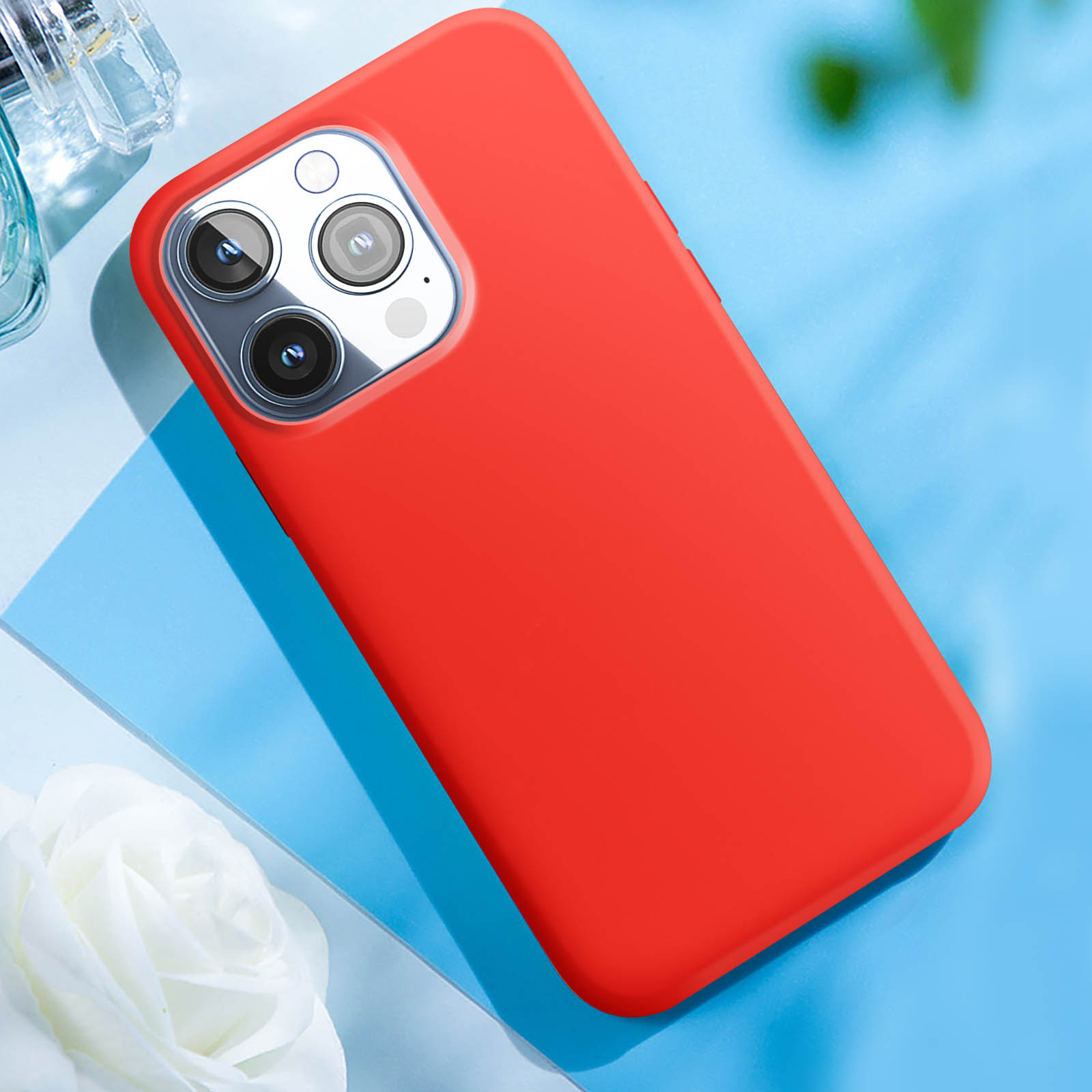 Custodia rossa per telefono su sfondo blu. Il telefono è nella custodia. Sono visibili tre lenti della fotocamera.
