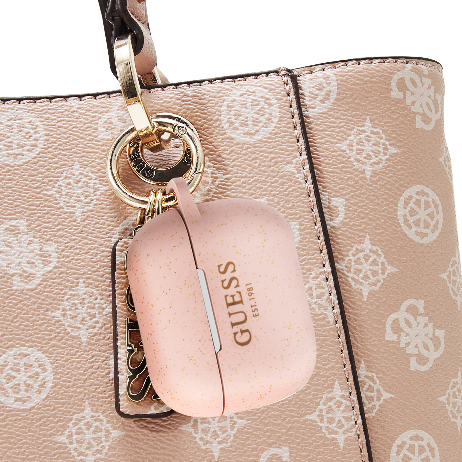 Funda rosa Guess para AirPods colgando de un bolso rosa Guess. Cierre dorado.