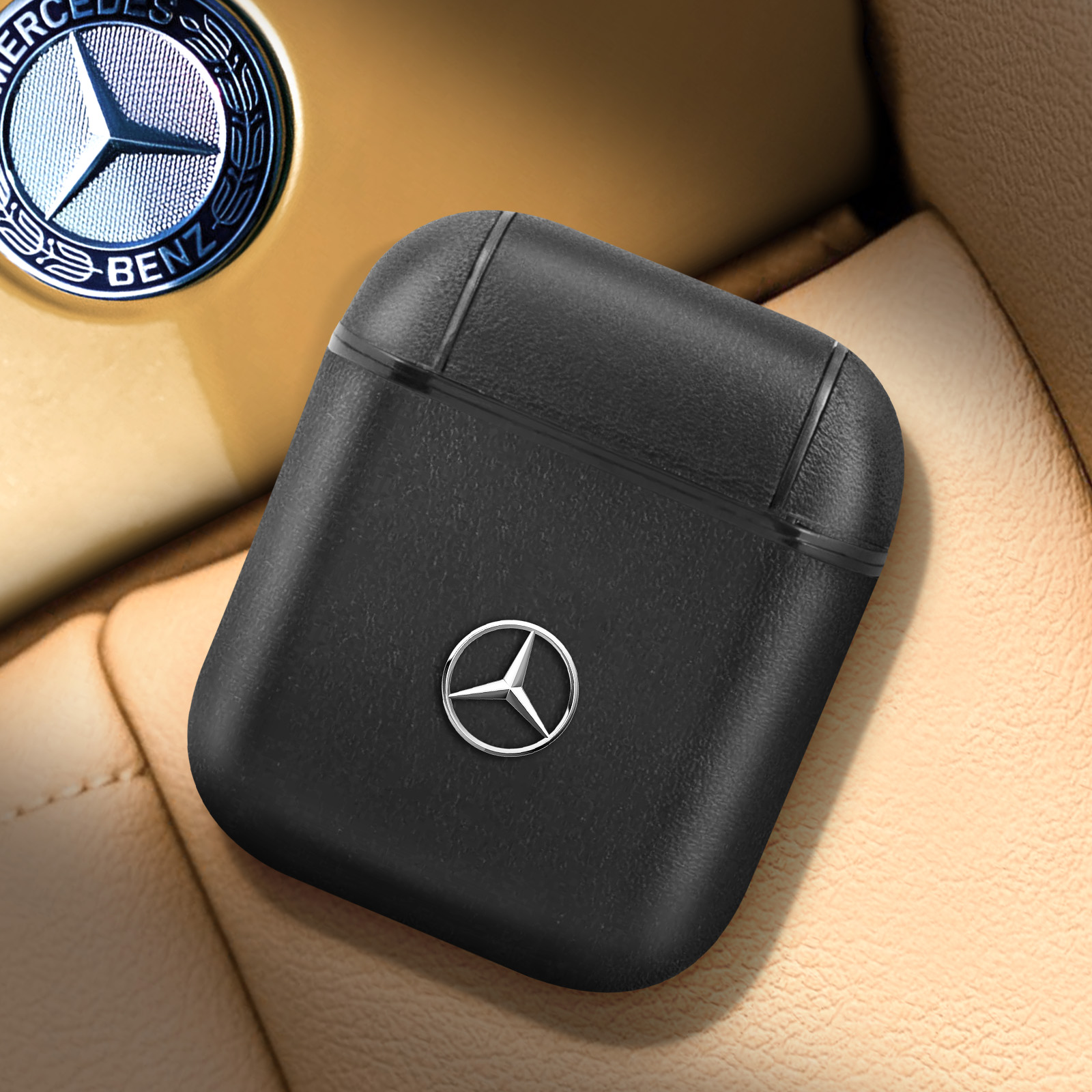 Funda de auriculares negra con el logo de Mercedes. Sobre un asiento beige, logo de Mercedes detrás.