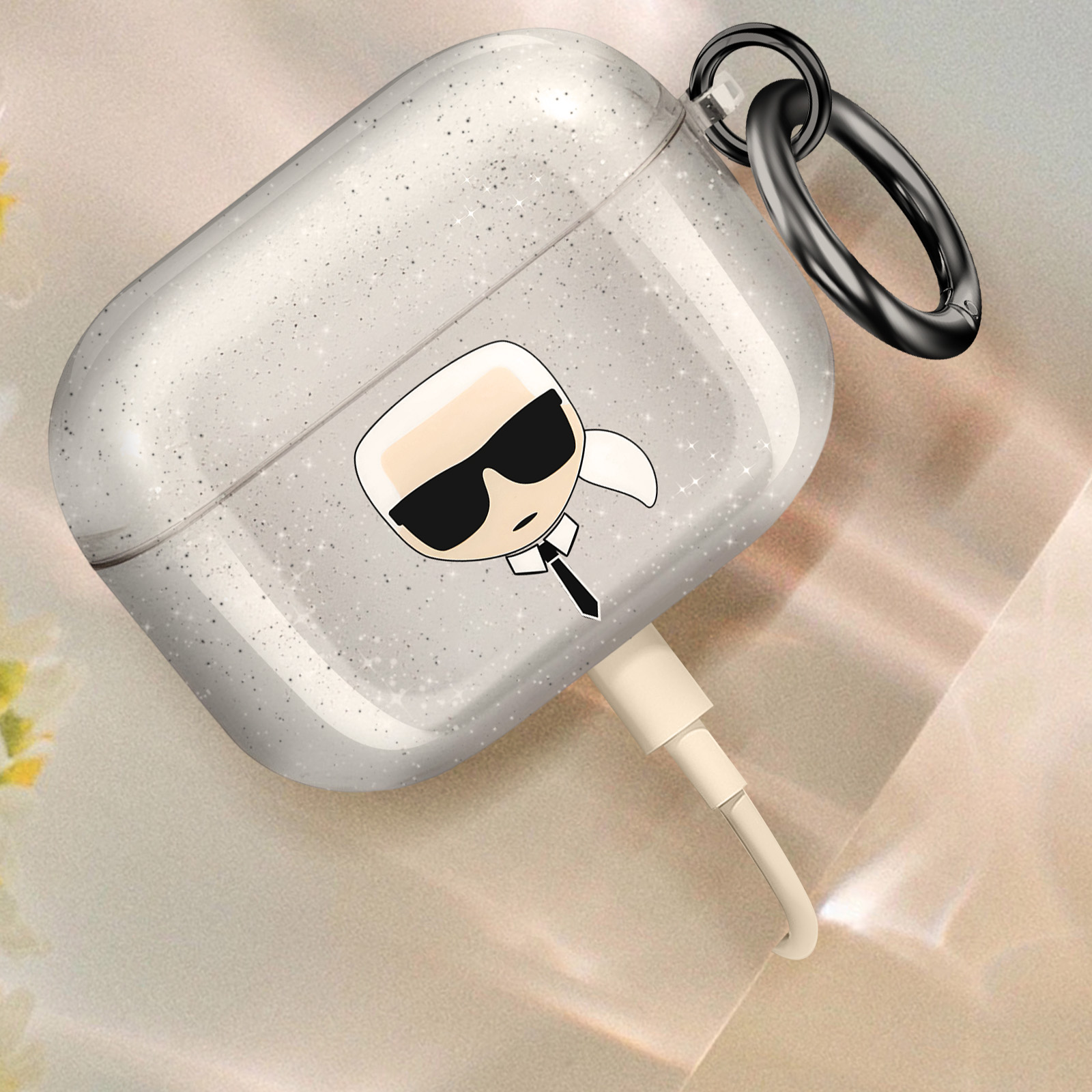 Funda transparente para AirPods con diseño Karl Lagerfeld. Un cable de carga está enchufado.