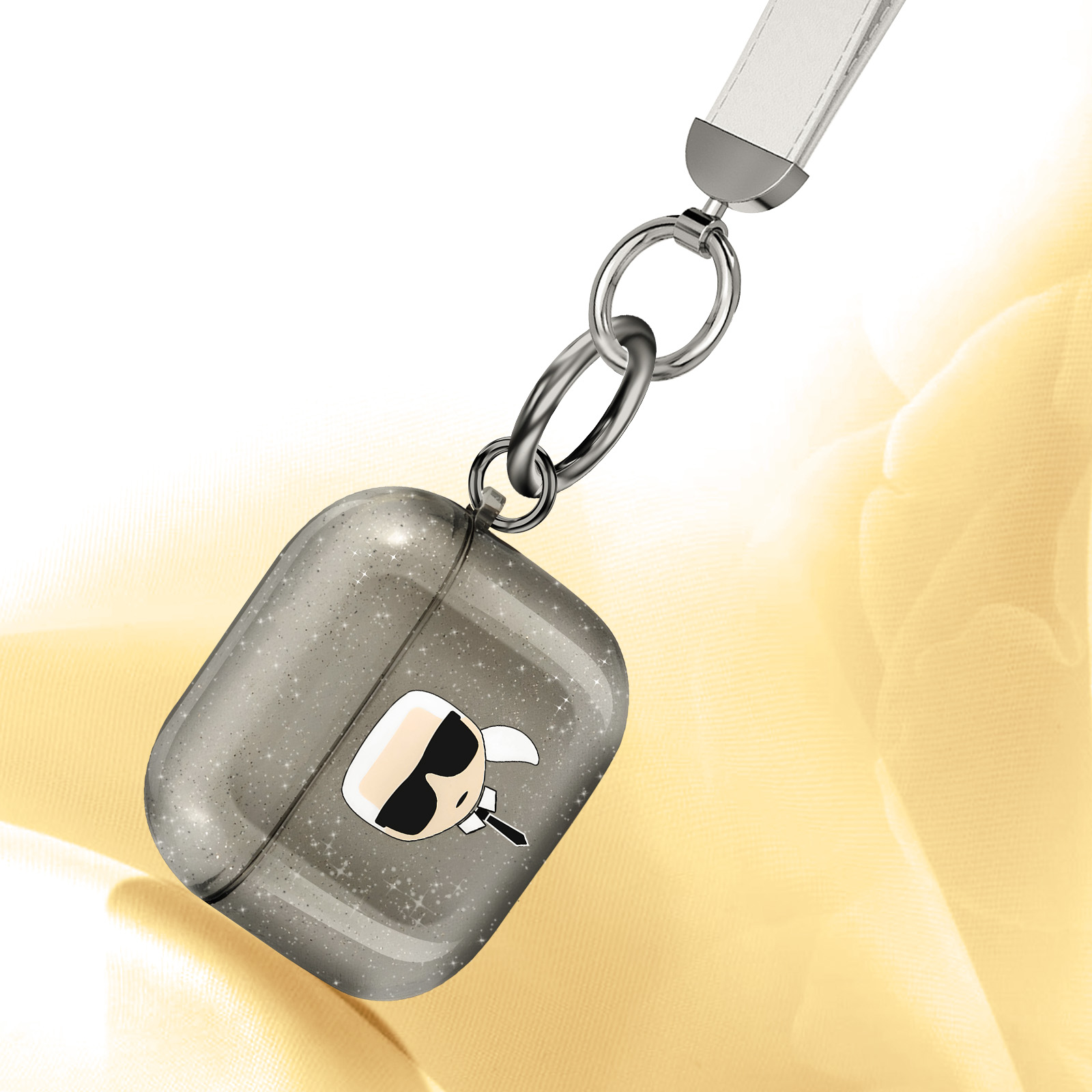 Funda Airpods gris con diseño de Karl Lagerfeld y correa blanca. Fondo amarillo.