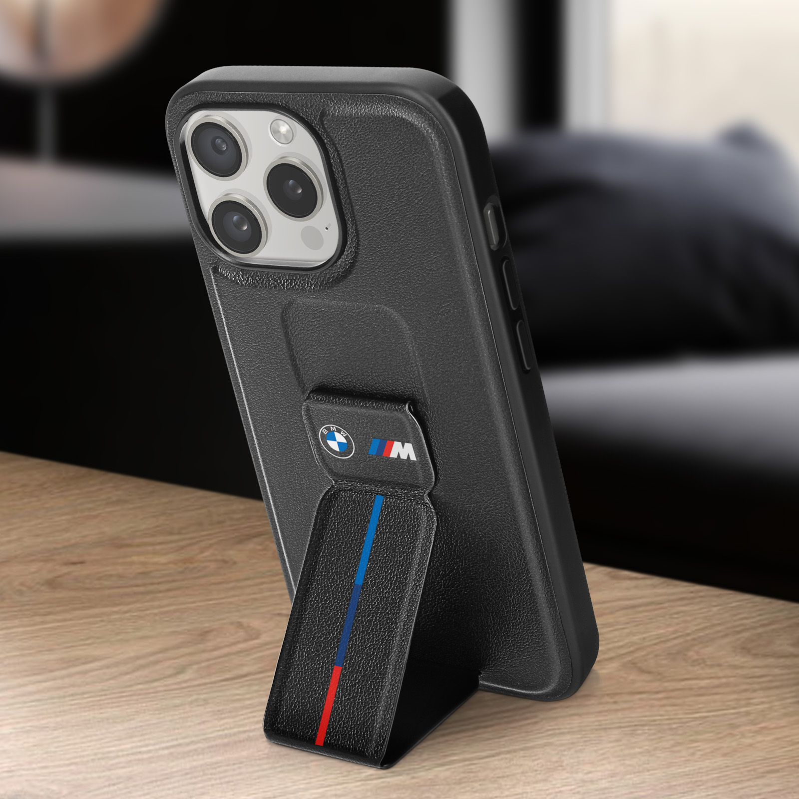 Custodia nera per telefono con logo BMW e cavalletto su superficie in legno.