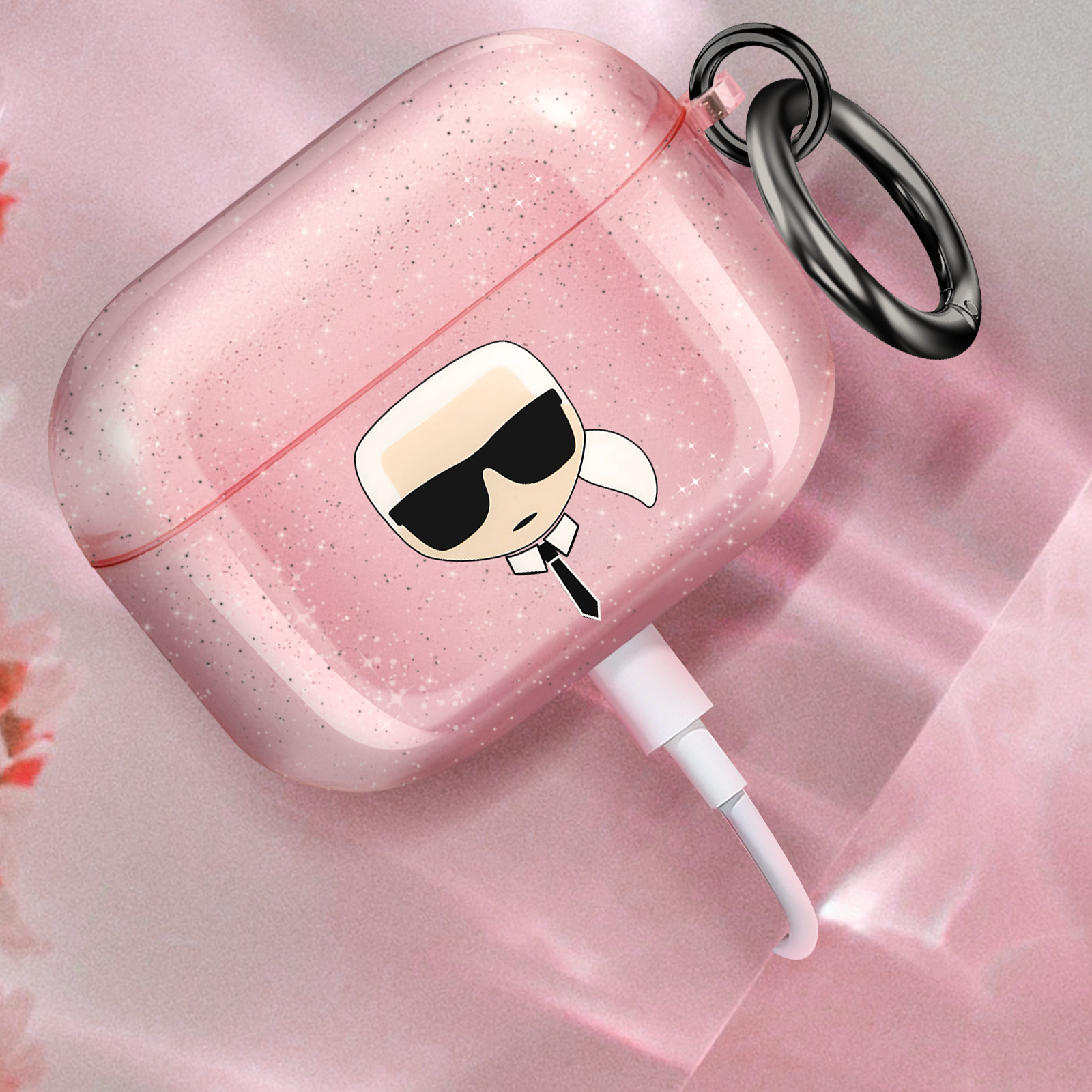 Una funda rosa y brillante para AirPods con una cara de dibujos animados y un cable de carga blanco.