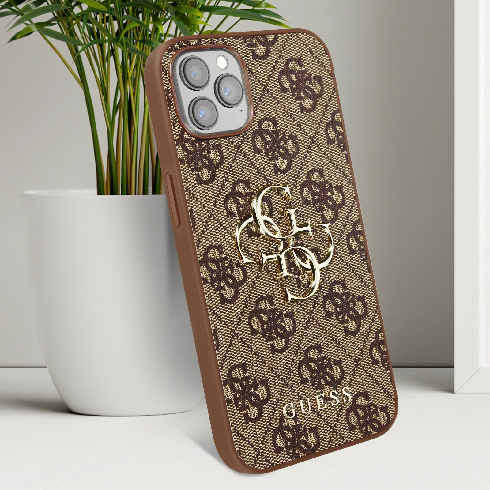 Custodia per telefono con motivo logo marrone, logo dorato e bordi marroni, accanto a un vaso bianco.