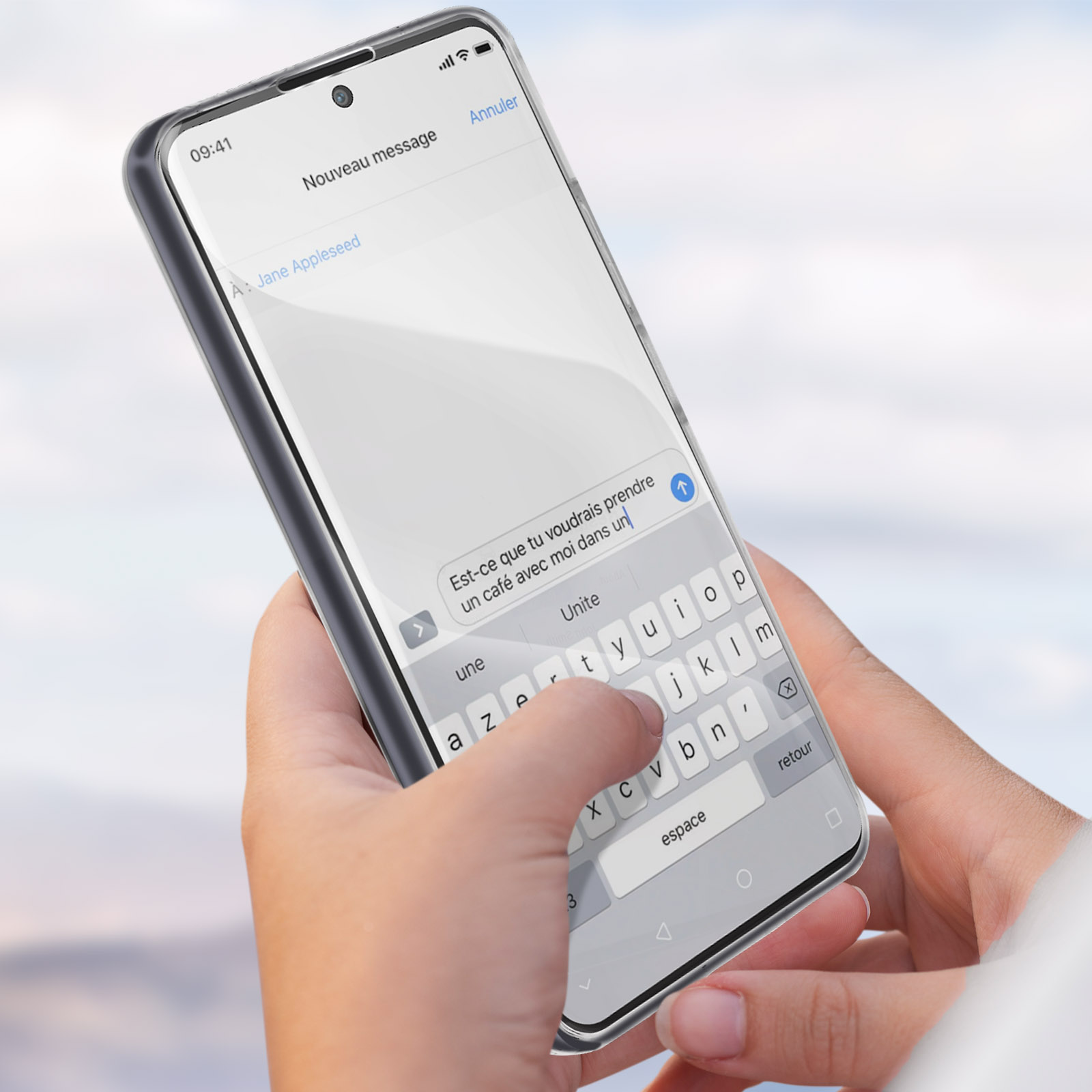 Una mano che tiene un telefono che mostra un messaggio di testo in francese e una tastiera.
