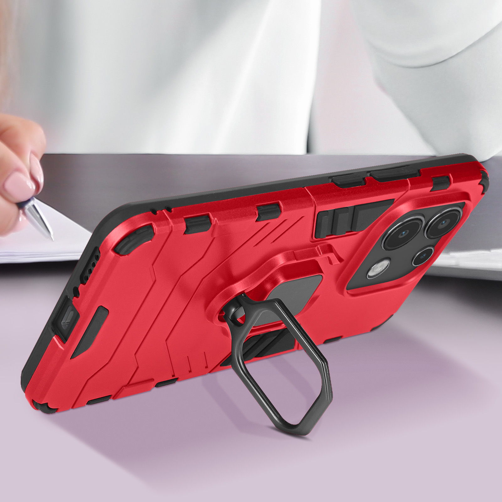 Rote Handyhülle mit Ringhalter. Telefon auf einem Schreibtisch, Stift in der Hand.