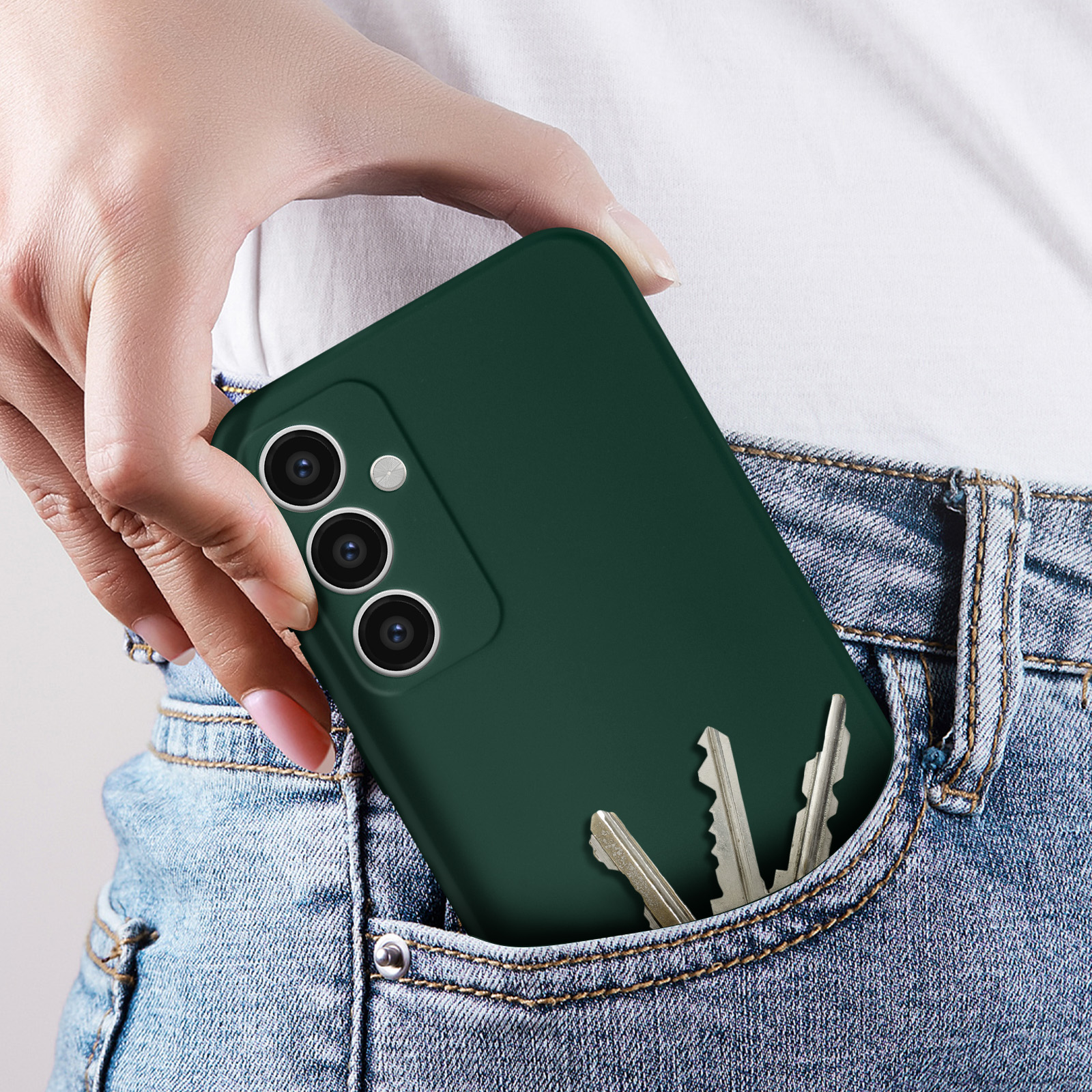 Mano che tiene un telefono in una custodia verde scuro. Le chiavi sono in tasca.
