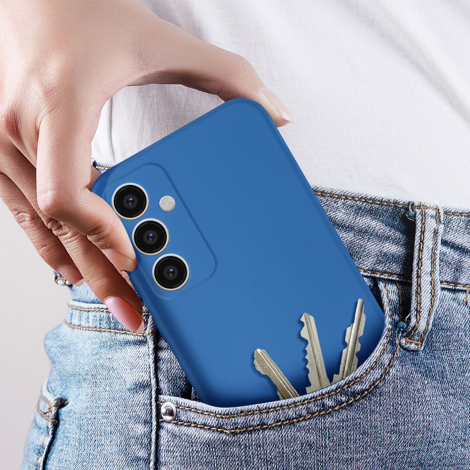 La mano di una persona che tiene un telefono in una custodia blu. Il telefono è in una tasca con delle chiavi.