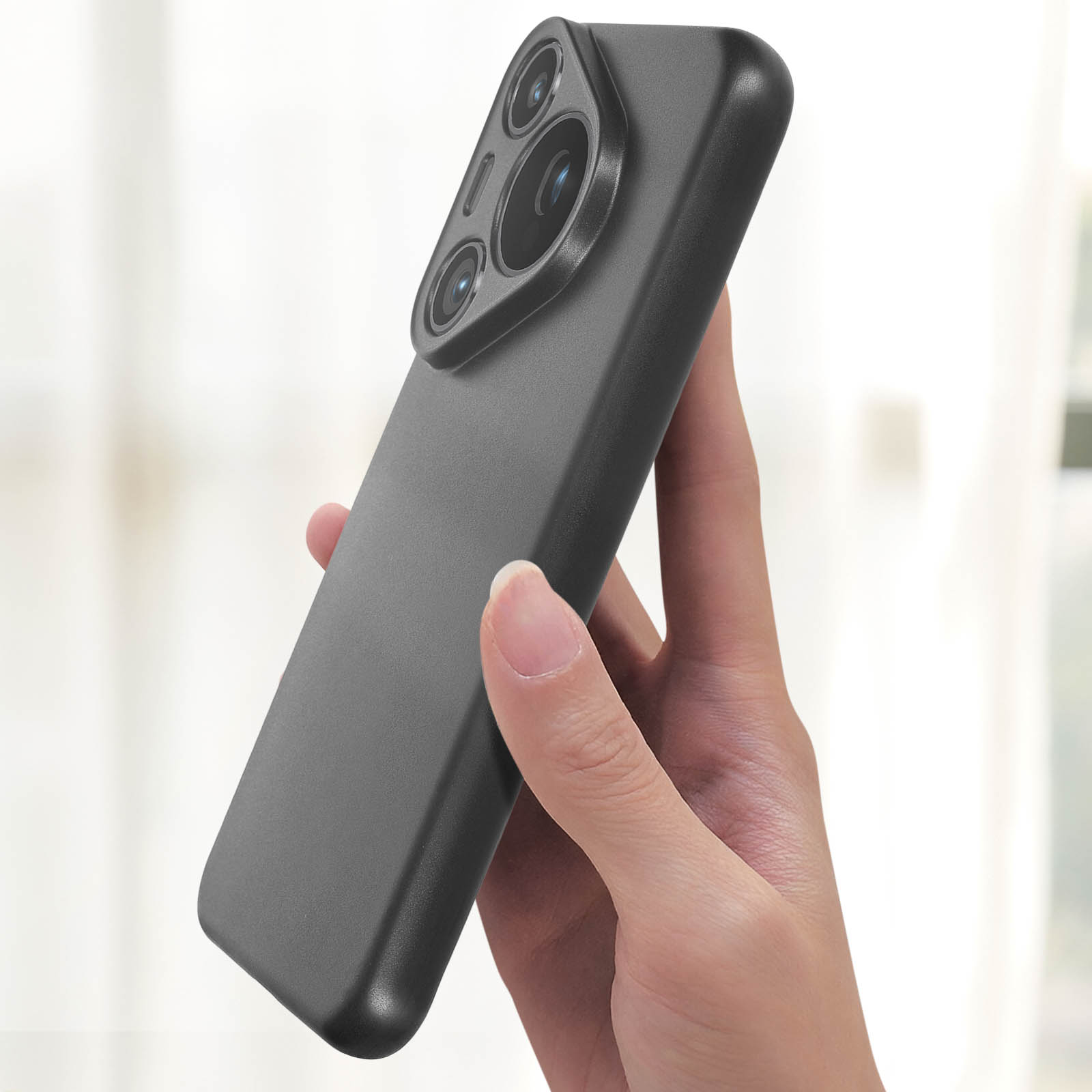 Mano che tiene un telefono nero con doppia fotocamera, su uno sfondo sfocato.