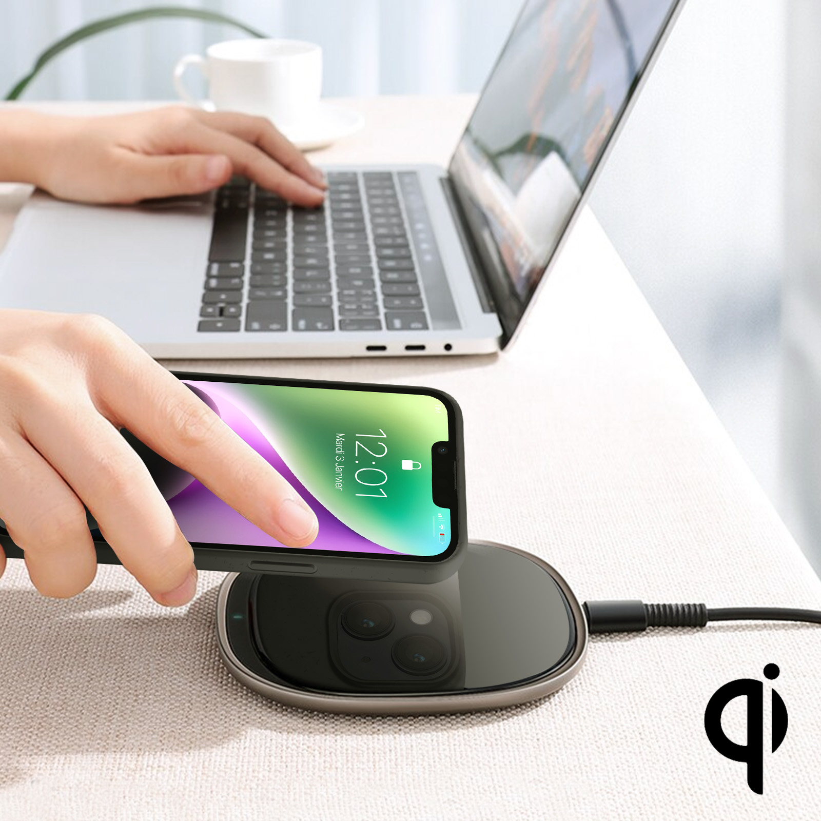 Una mano usa un telefono e un caricatore wireless. Sono visibili un laptop e un logo ql.
